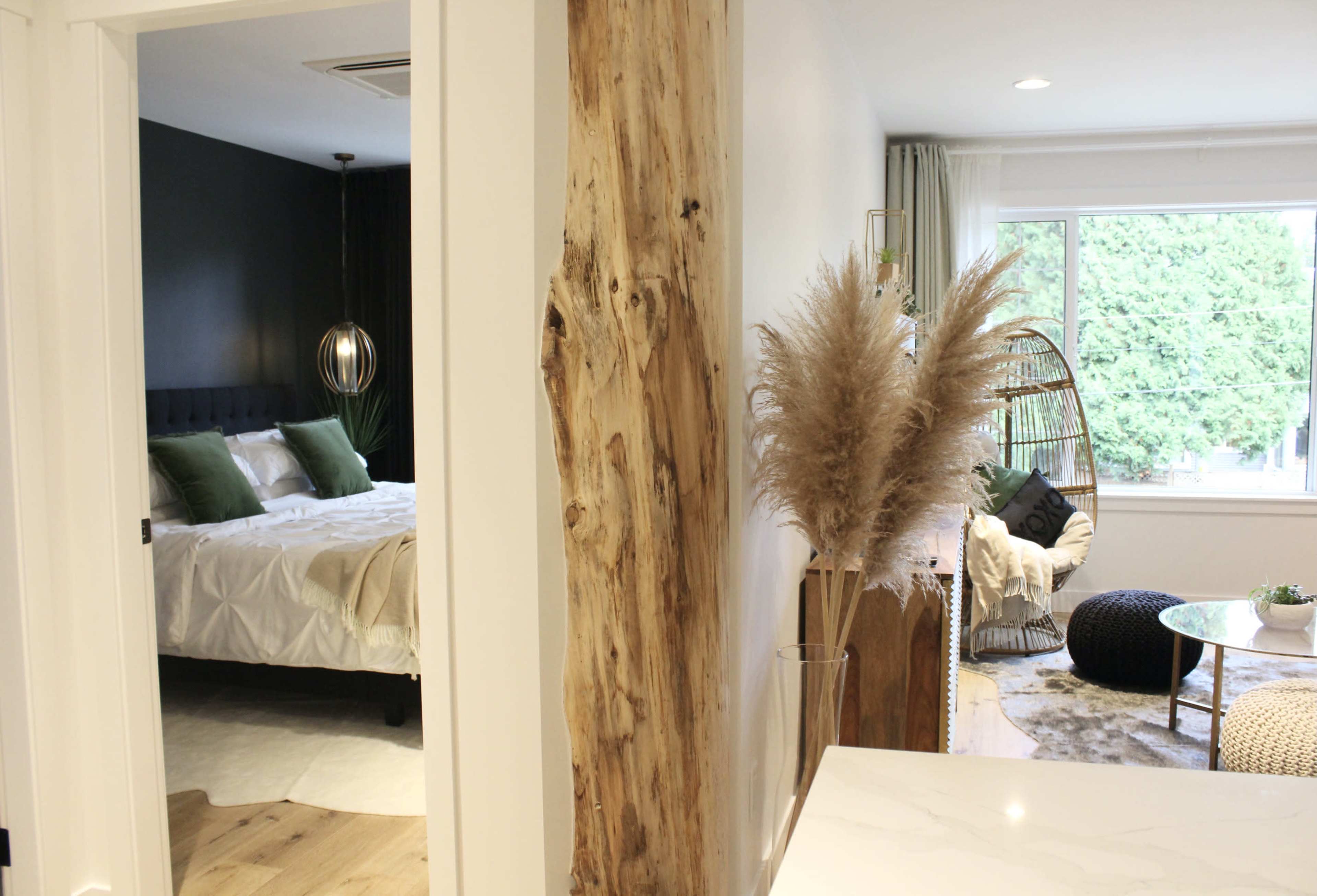 A modern interior space featuring a cozy living area with a seating arrangement, leading to a bedroom visible through an open doorway.