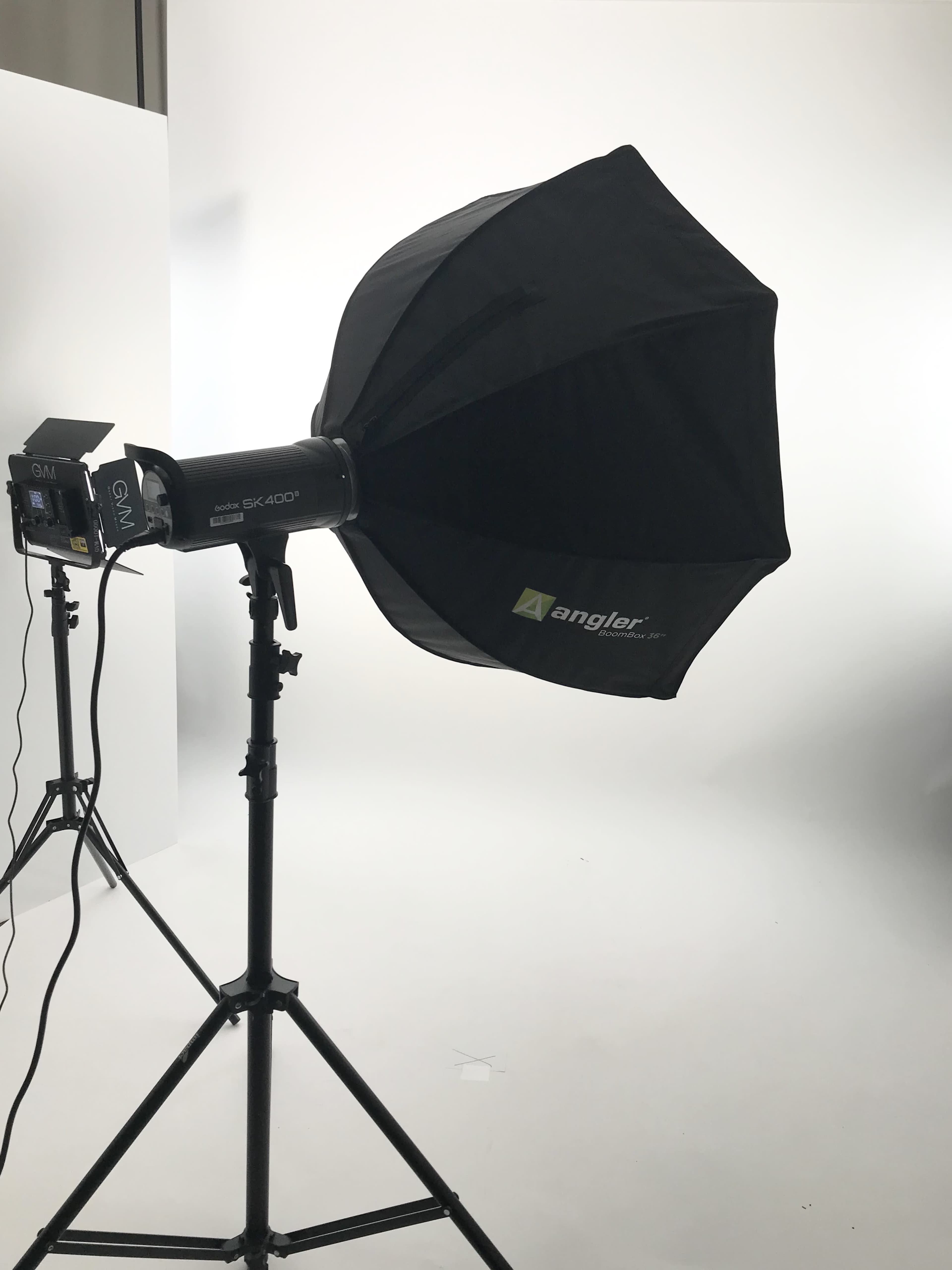 A softbox light mounted on a stand, positioned in a studio setting with a plain white background.