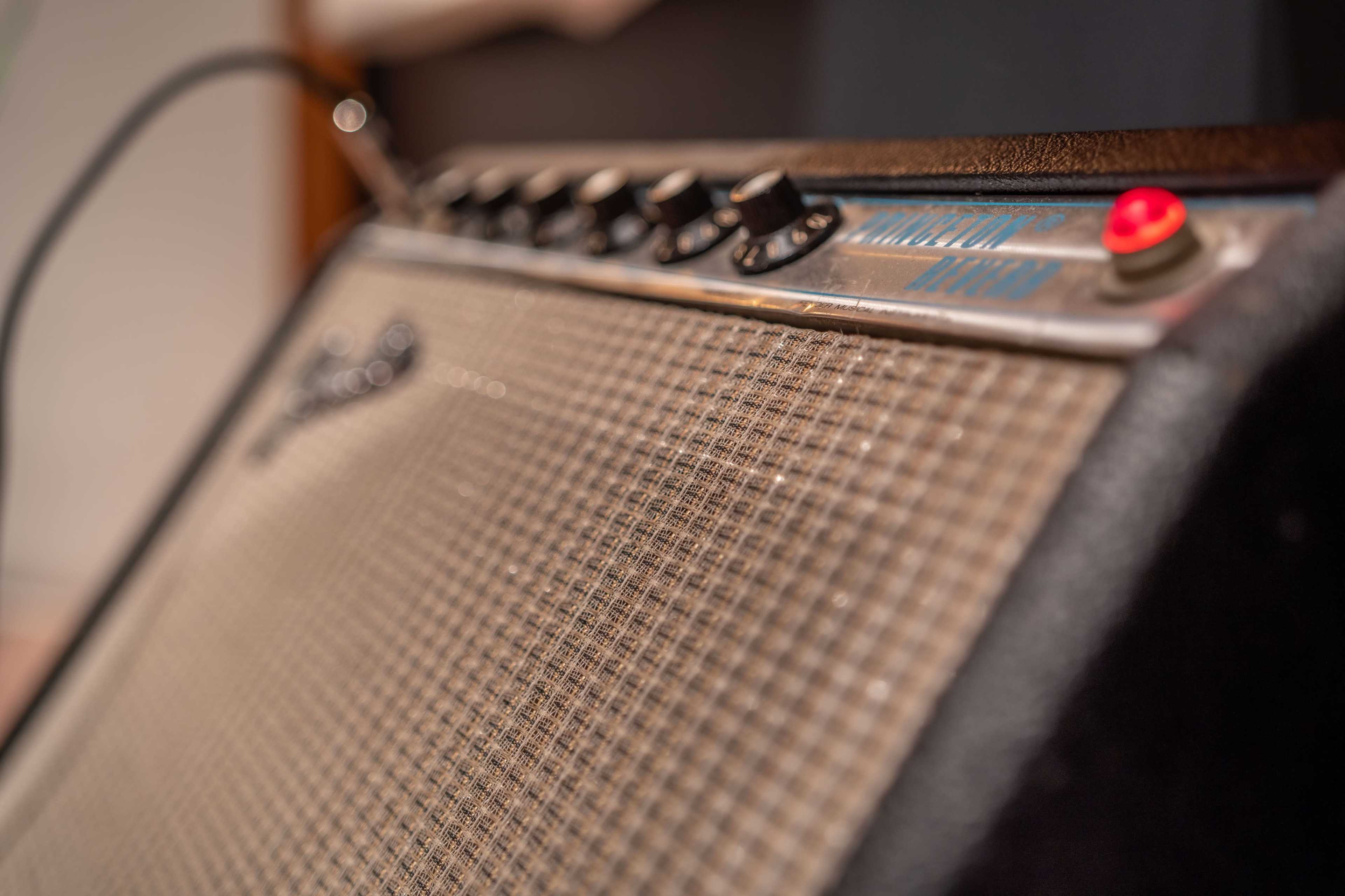 A close-up of a vintage amplifier with knobs and a red power indicator.