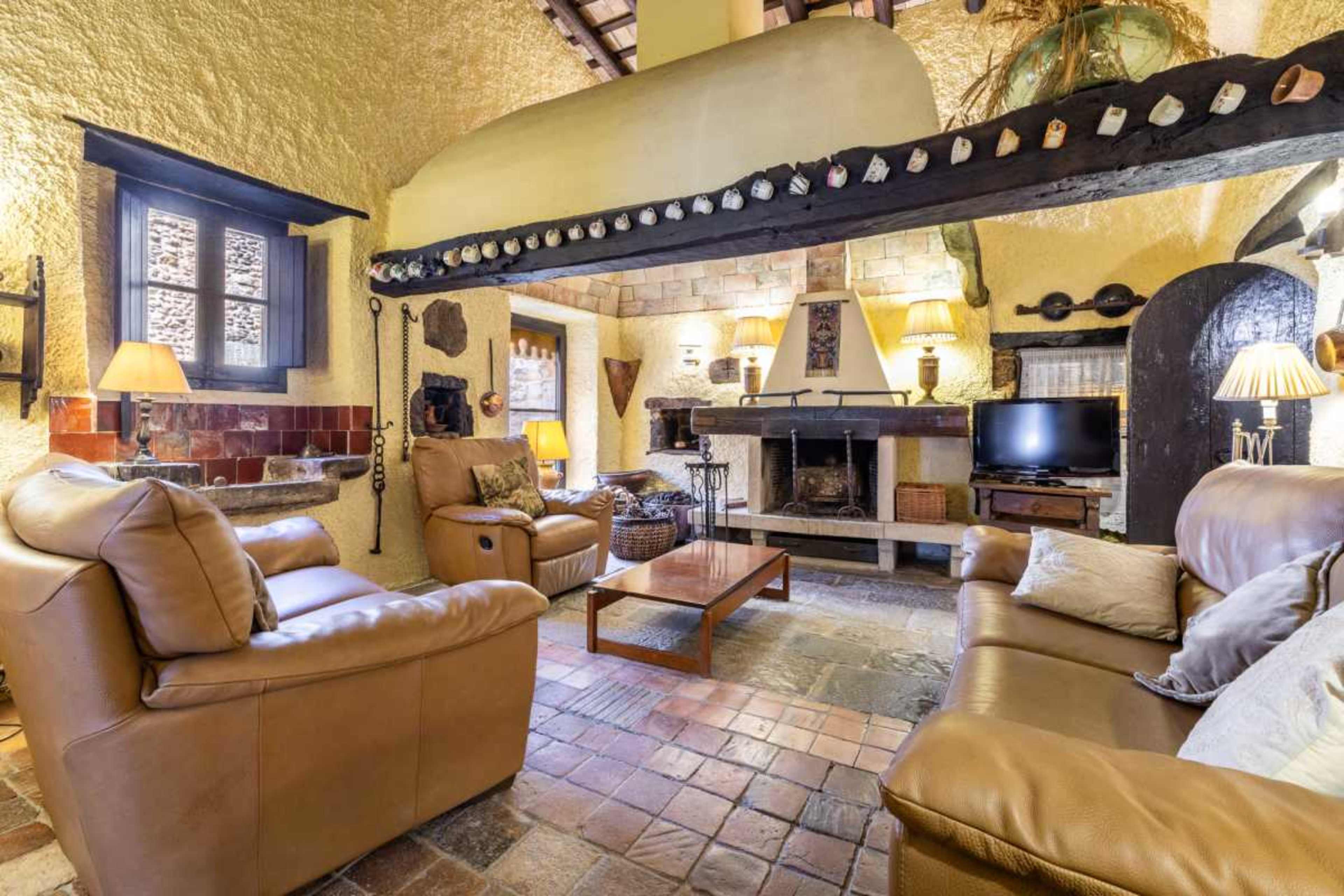 The image shows a cozy living room with leather sofas, a coffee table, and a stone fireplace, all set against textured yellow walls.