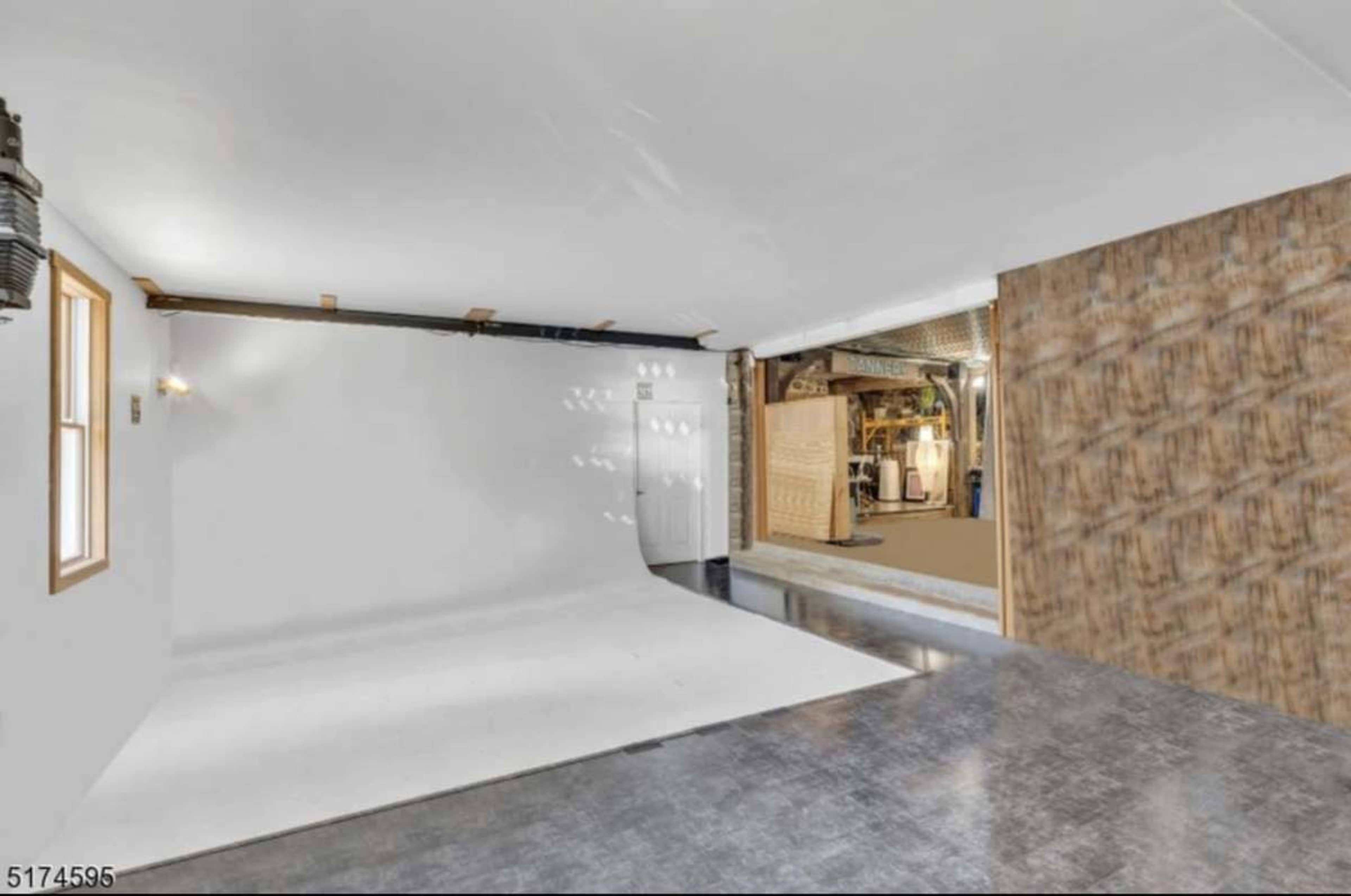The image shows an empty room with a white backdrop and a partially open wall revealing another area behind it.