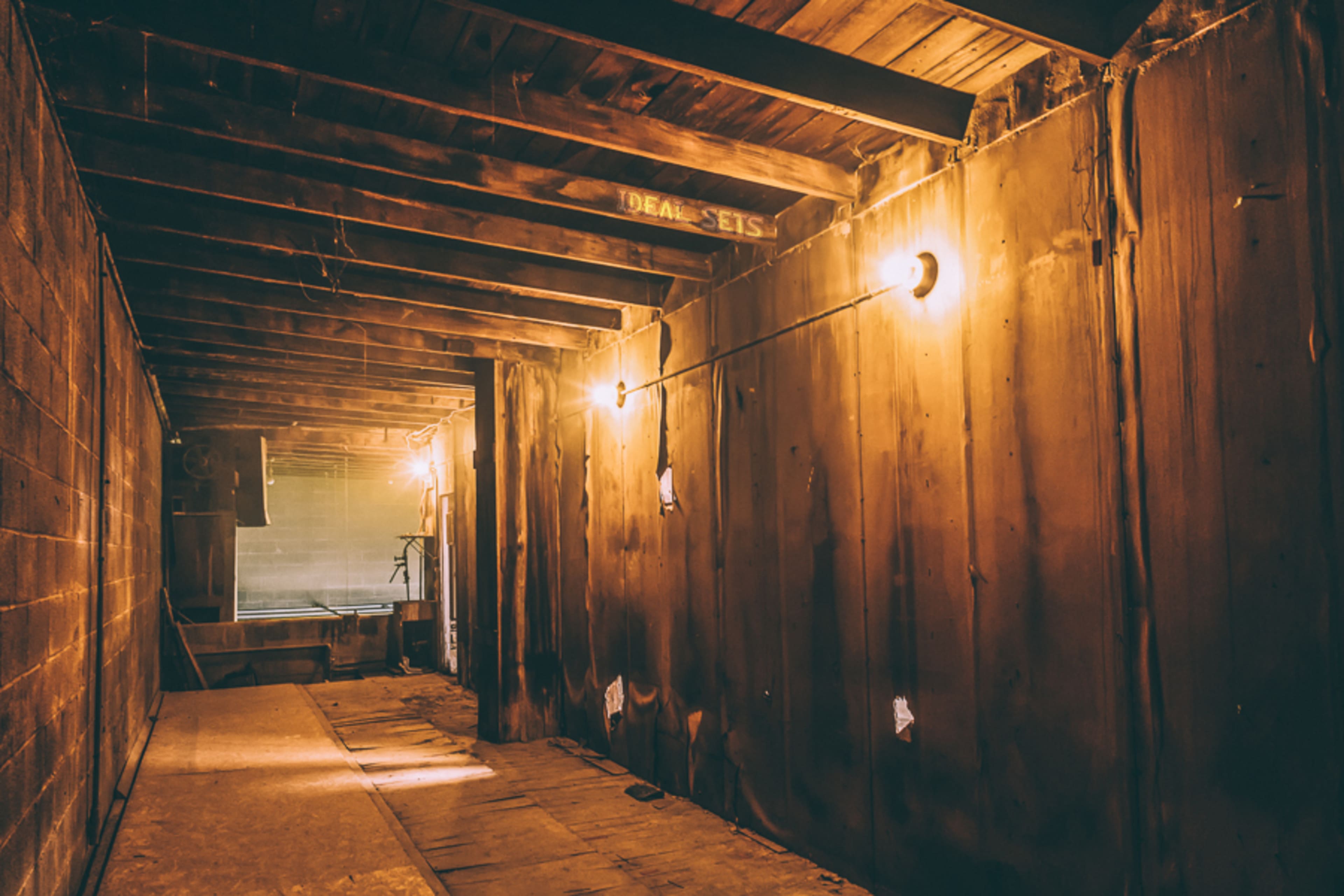 A dimly lit, unfinished wooden interior of a building with exposed beams and walls.