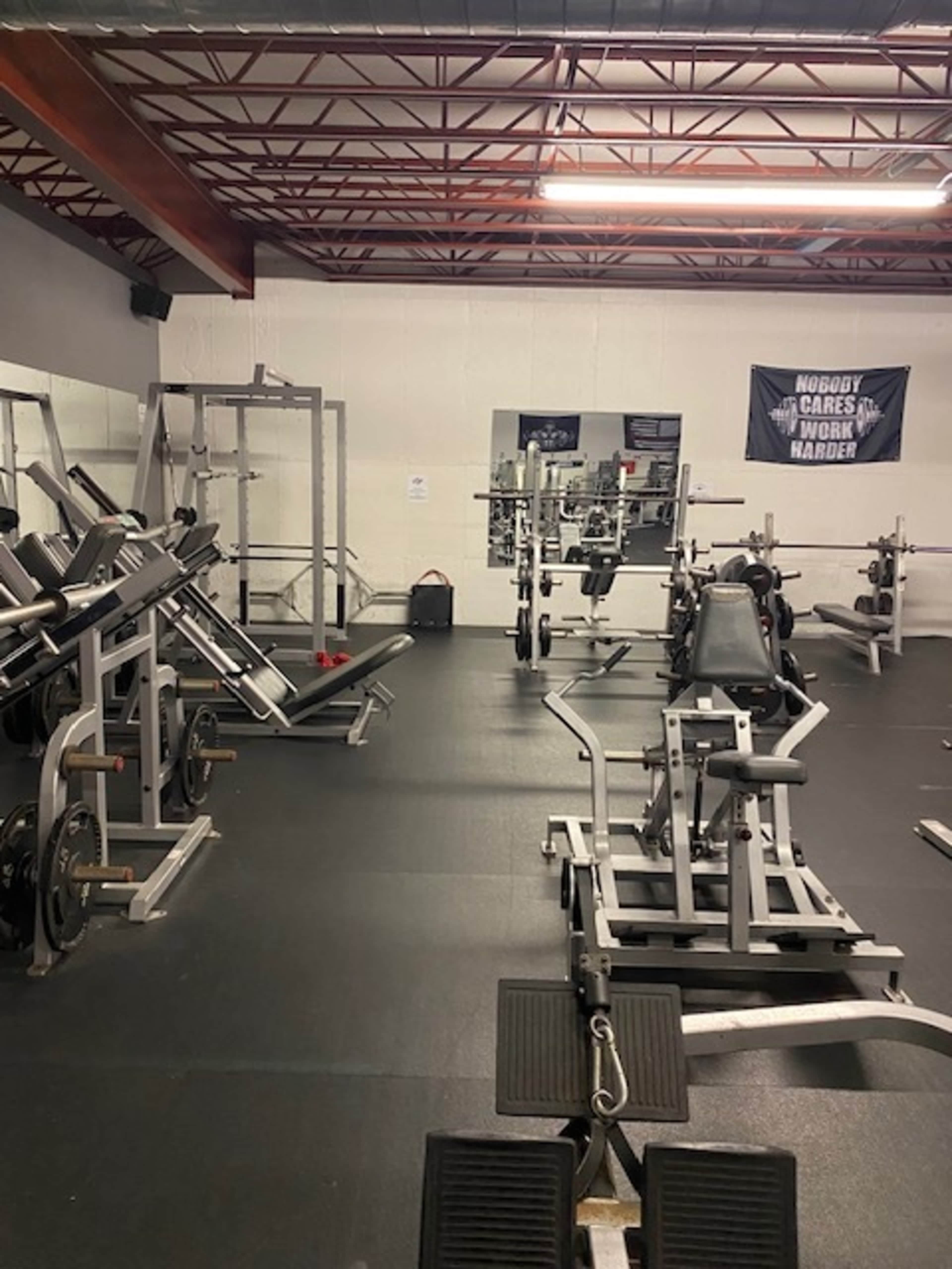 A gym with various weightlifting equipment and fitness machines arranged in a spacious room.