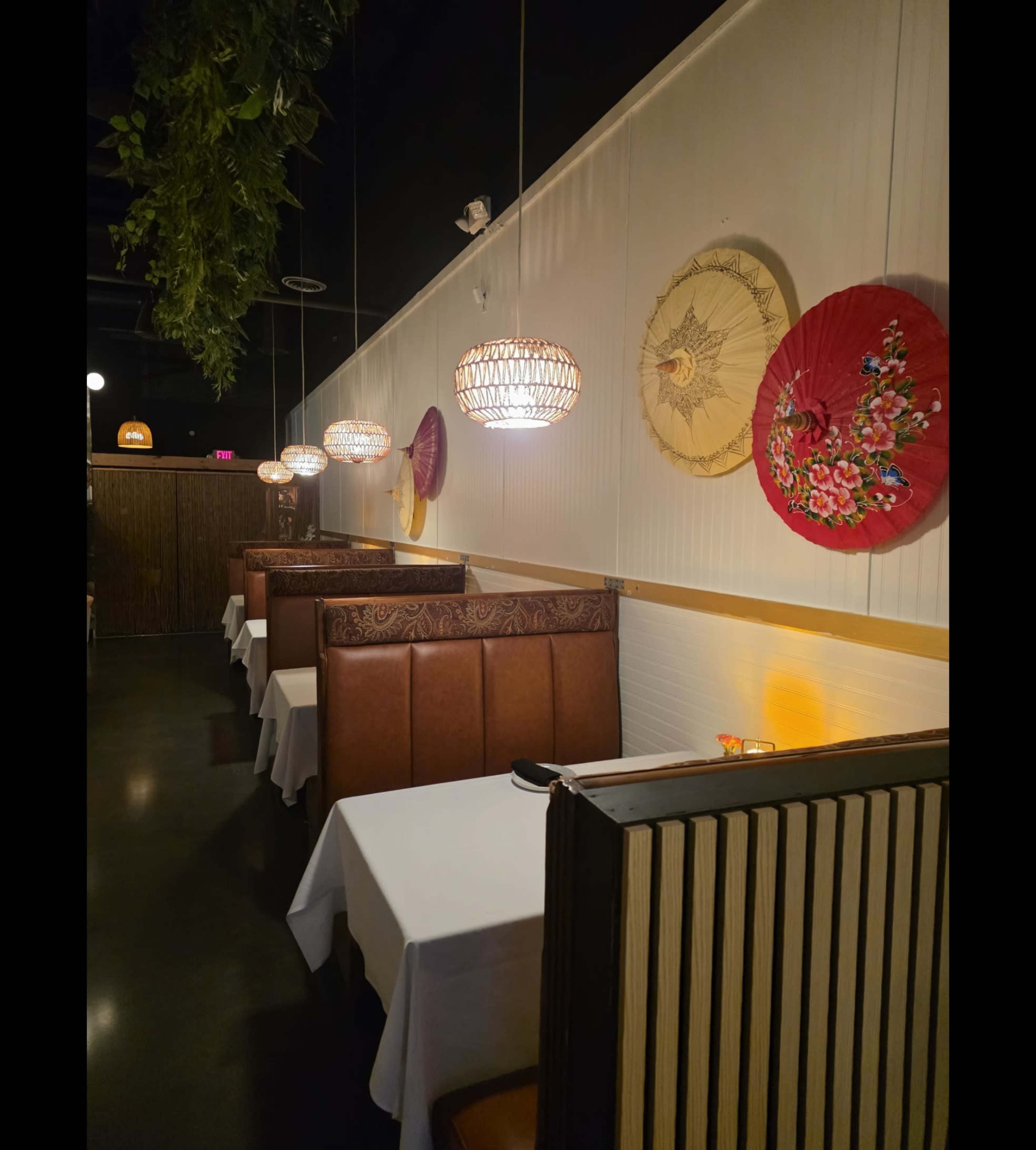 The image shows a dimly lit restaurant with brown booths, white tablecloths, and decorative hanging lanterns and wall decor.