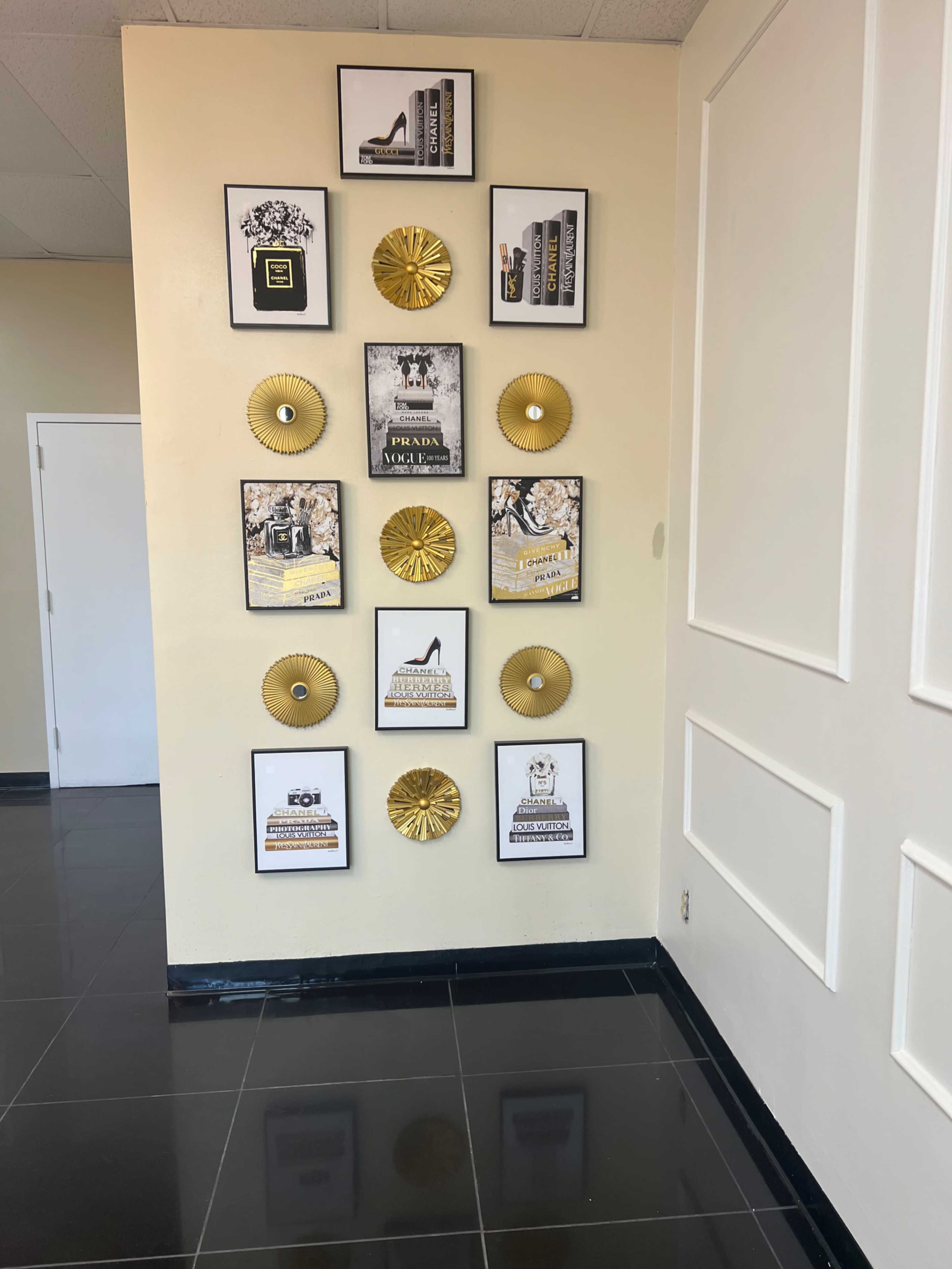 A wall adorned with framed artwork and decorative pieces, including books, fashion-related prints, and golden circular decor.