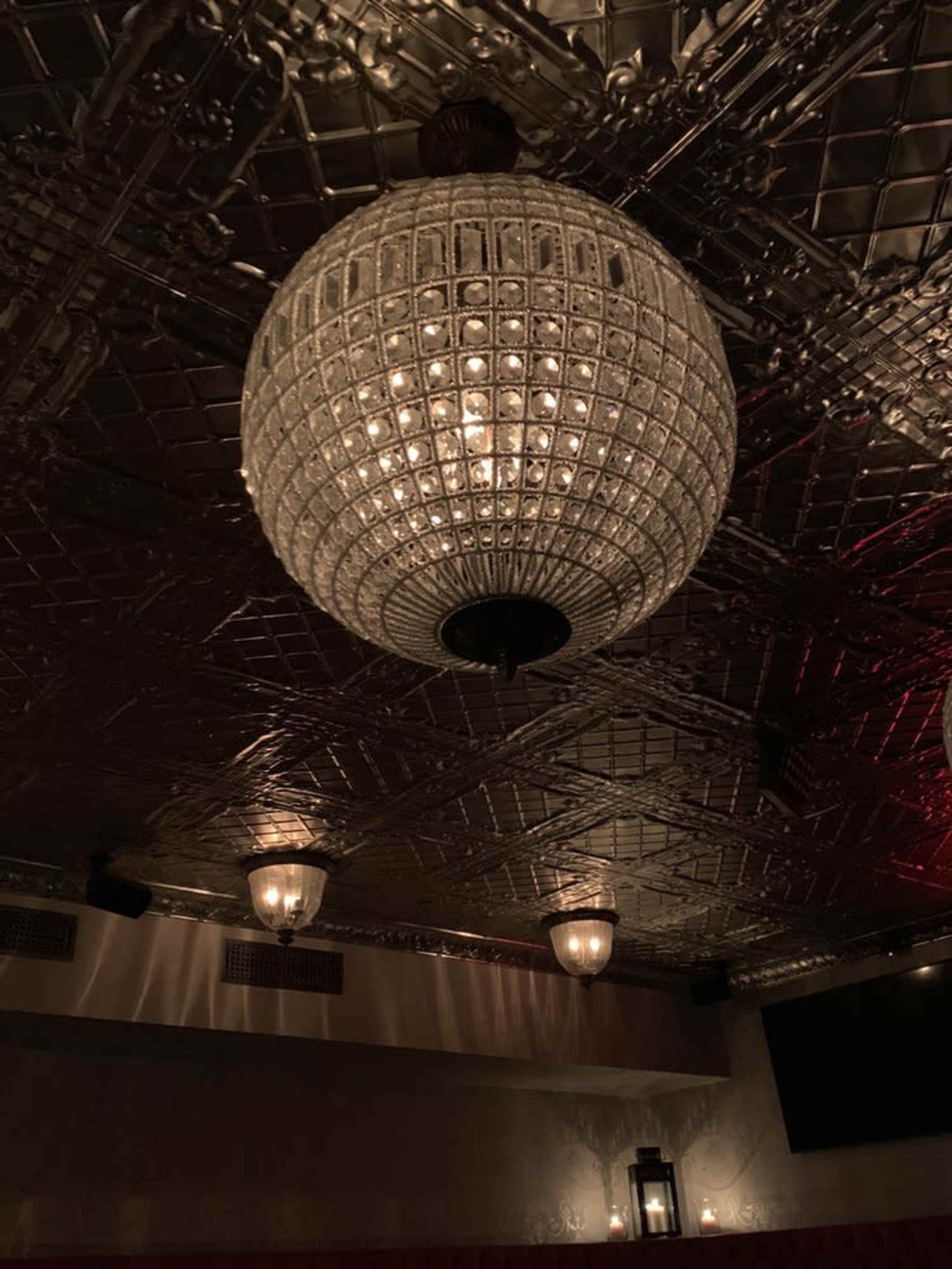 A large, faceted glass chandelier hangs from a decorative ceiling.