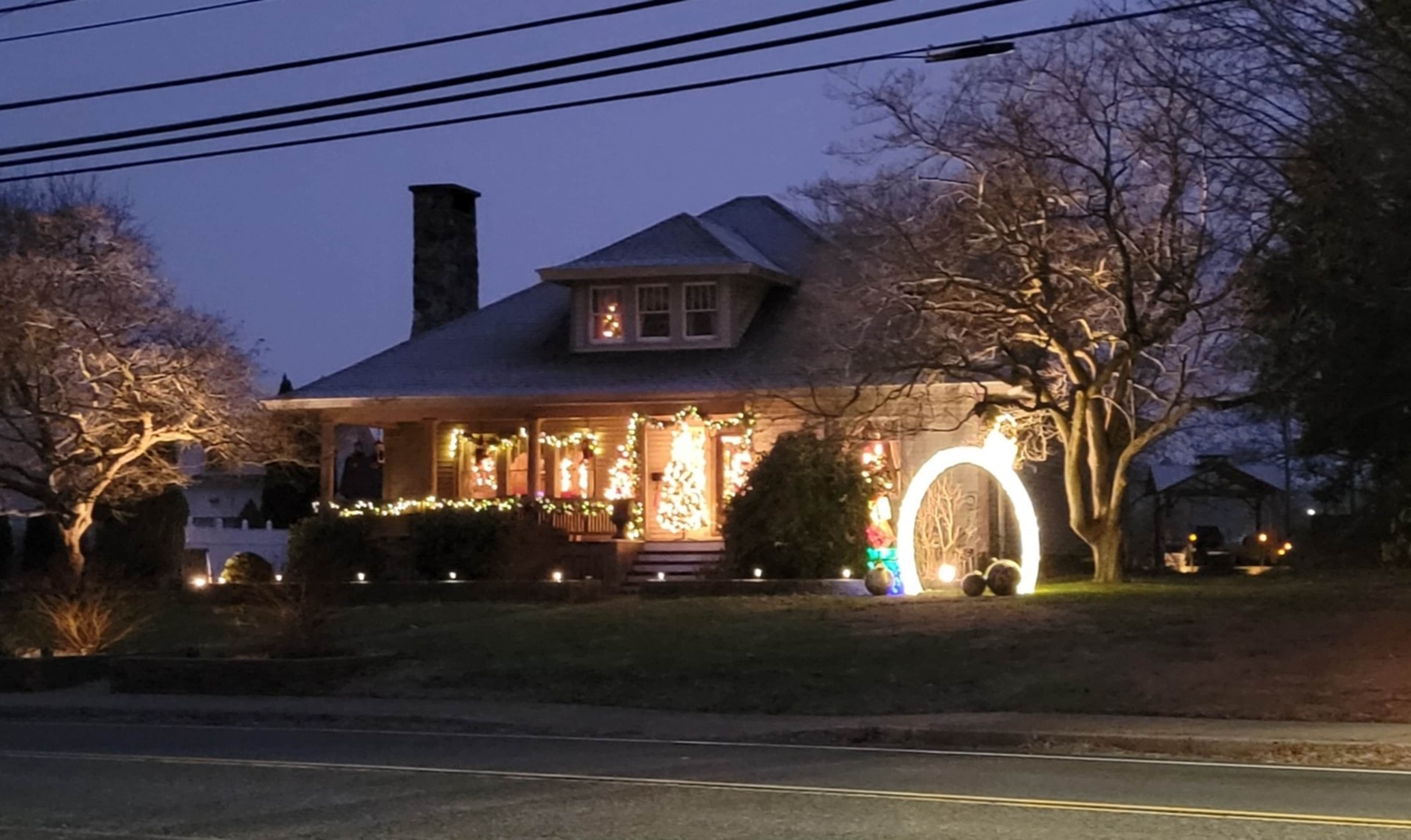 A house is illuminated with festive lights and decorations during twilight.