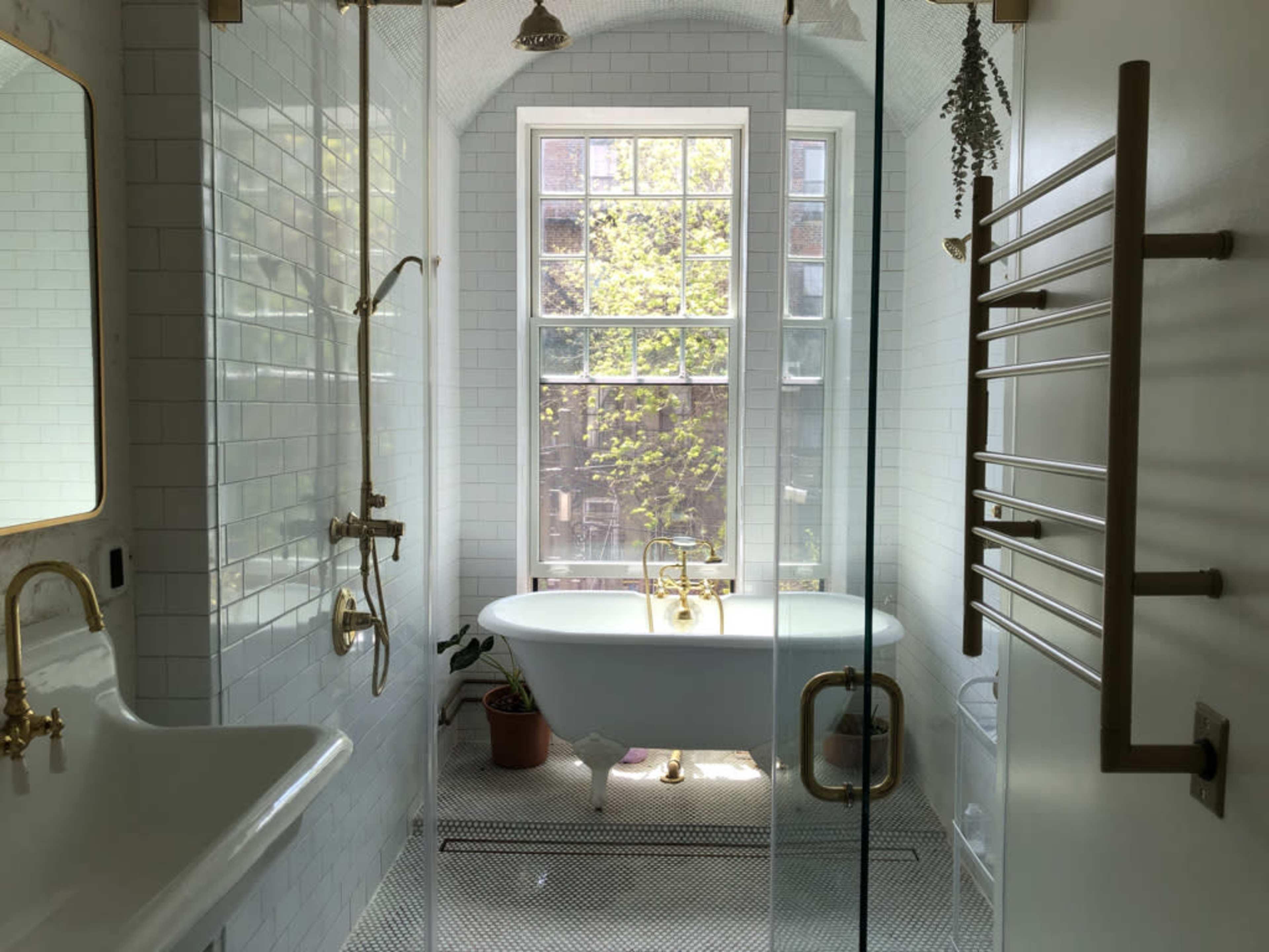 The image depicts a modern bathroom featuring a freestanding tub, a spacious walk-in shower, and a large window allowing natural light to illuminate the space.