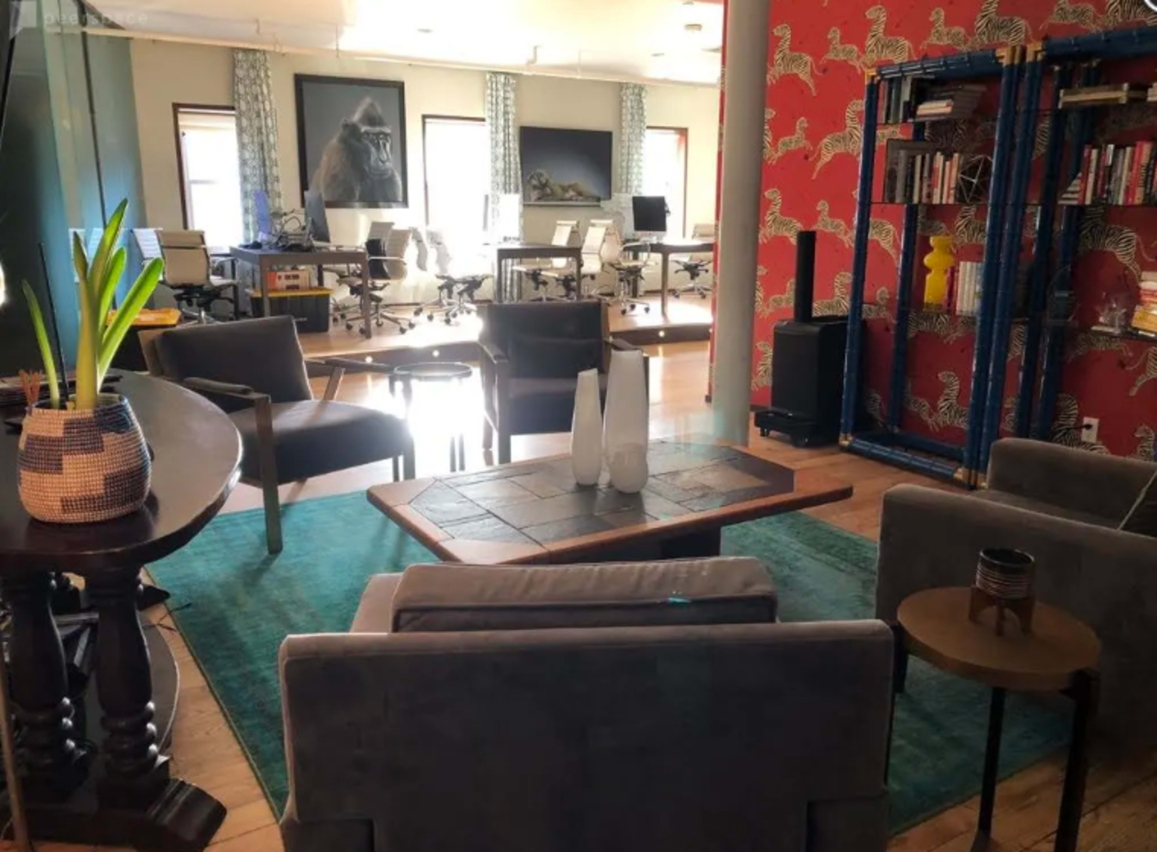 A modern office space with contemporary furniture, a colorful accent wall, and several workstations in the background.