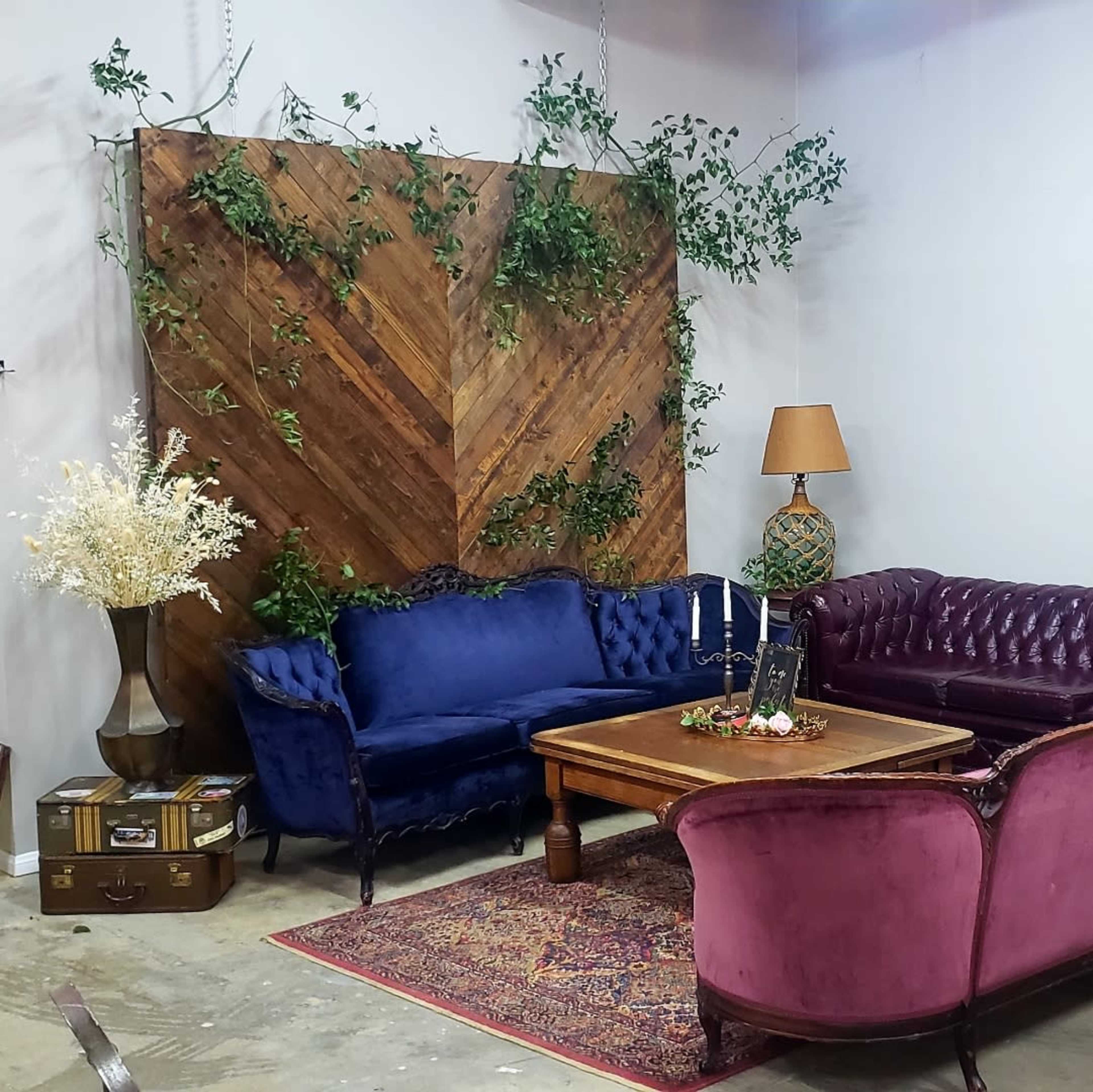 A seating area with a wooden accent wall, two purple sofas, a wooden coffee table adorned with decorative items, and a floor lamp.