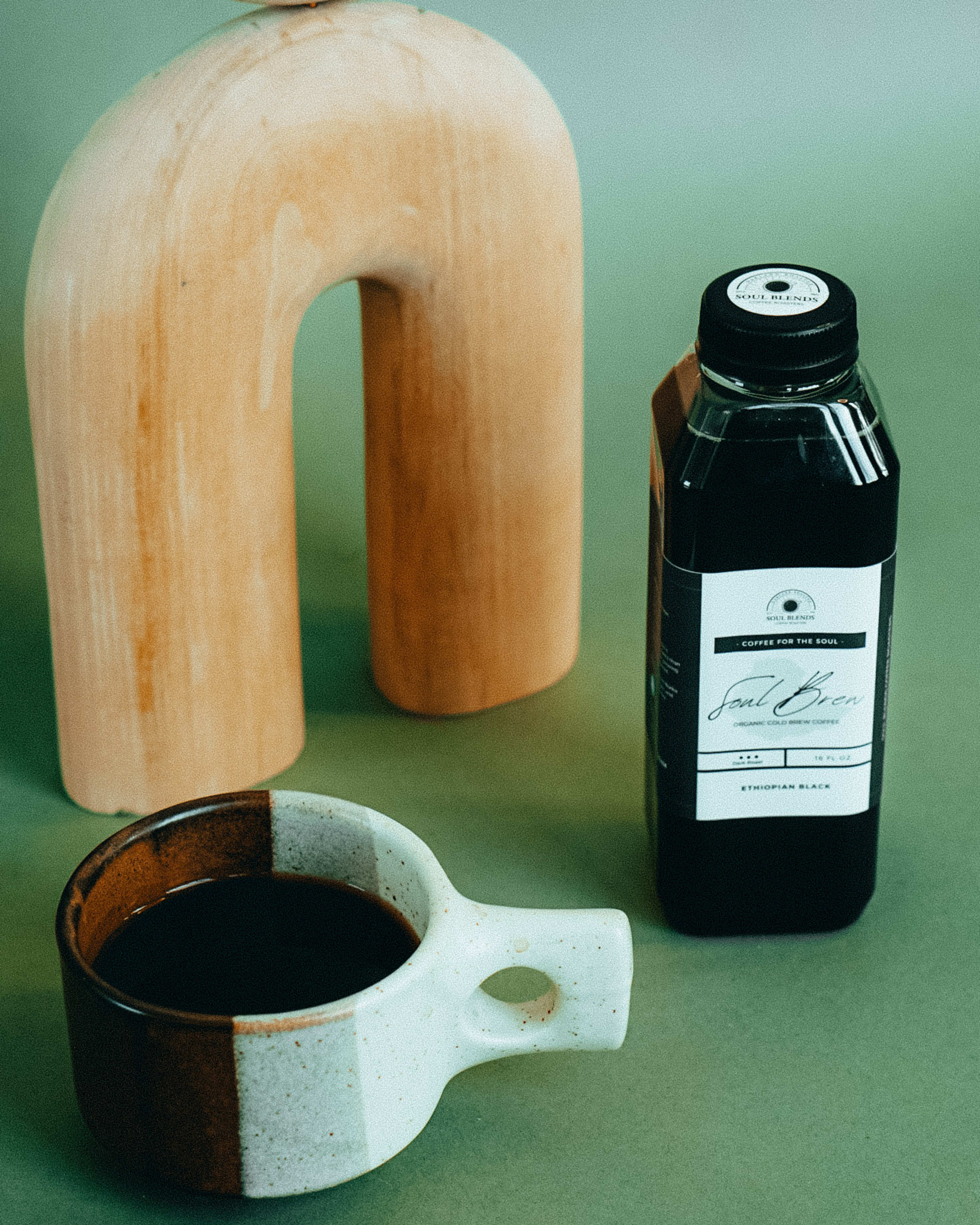 Un objeto de madera junto a una taza de café para una sesión de fotos de producto.