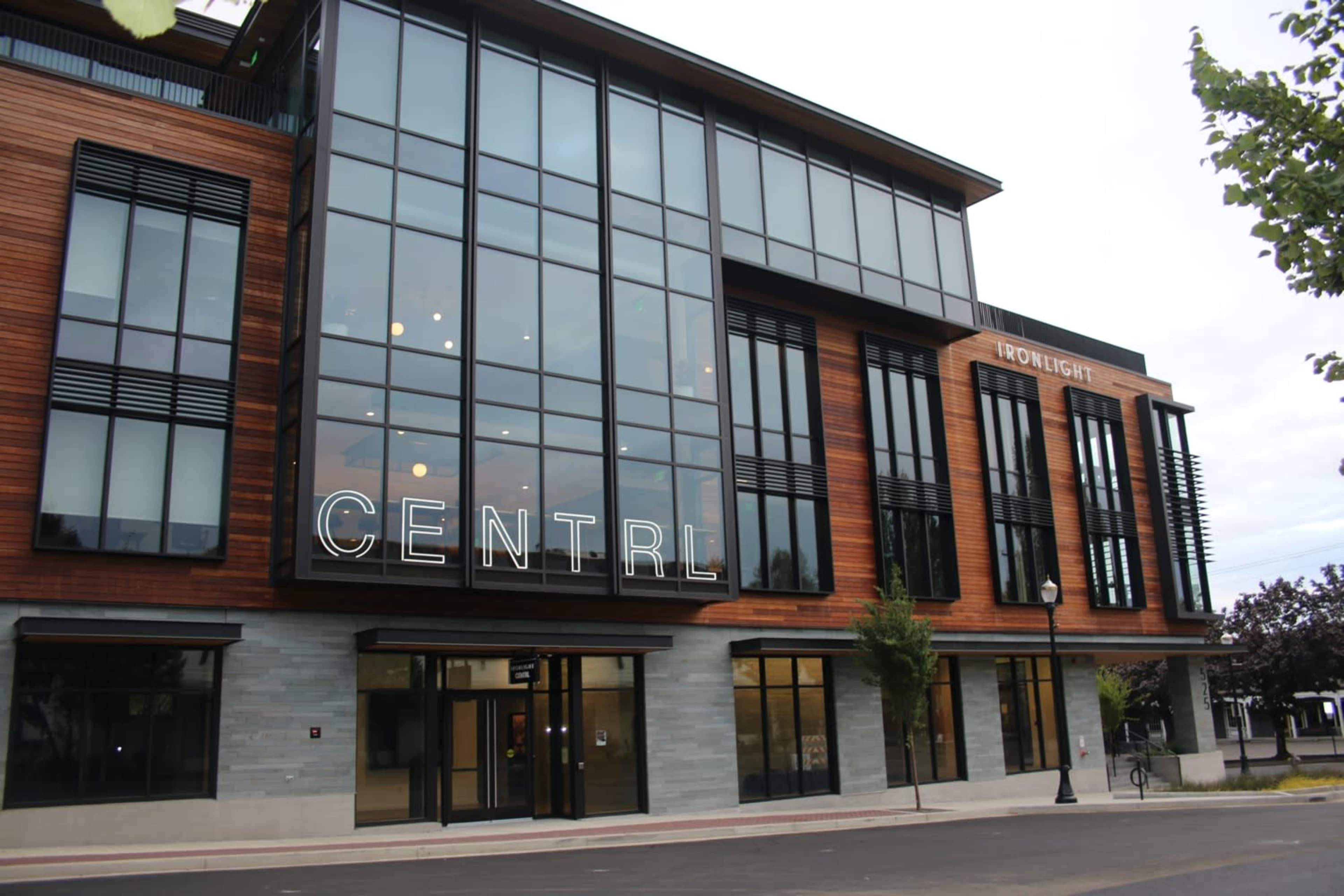 The image shows a modern commercial building with large glass windows and wooden accents, featuring the name "CENTRAL" in illuminated letters.