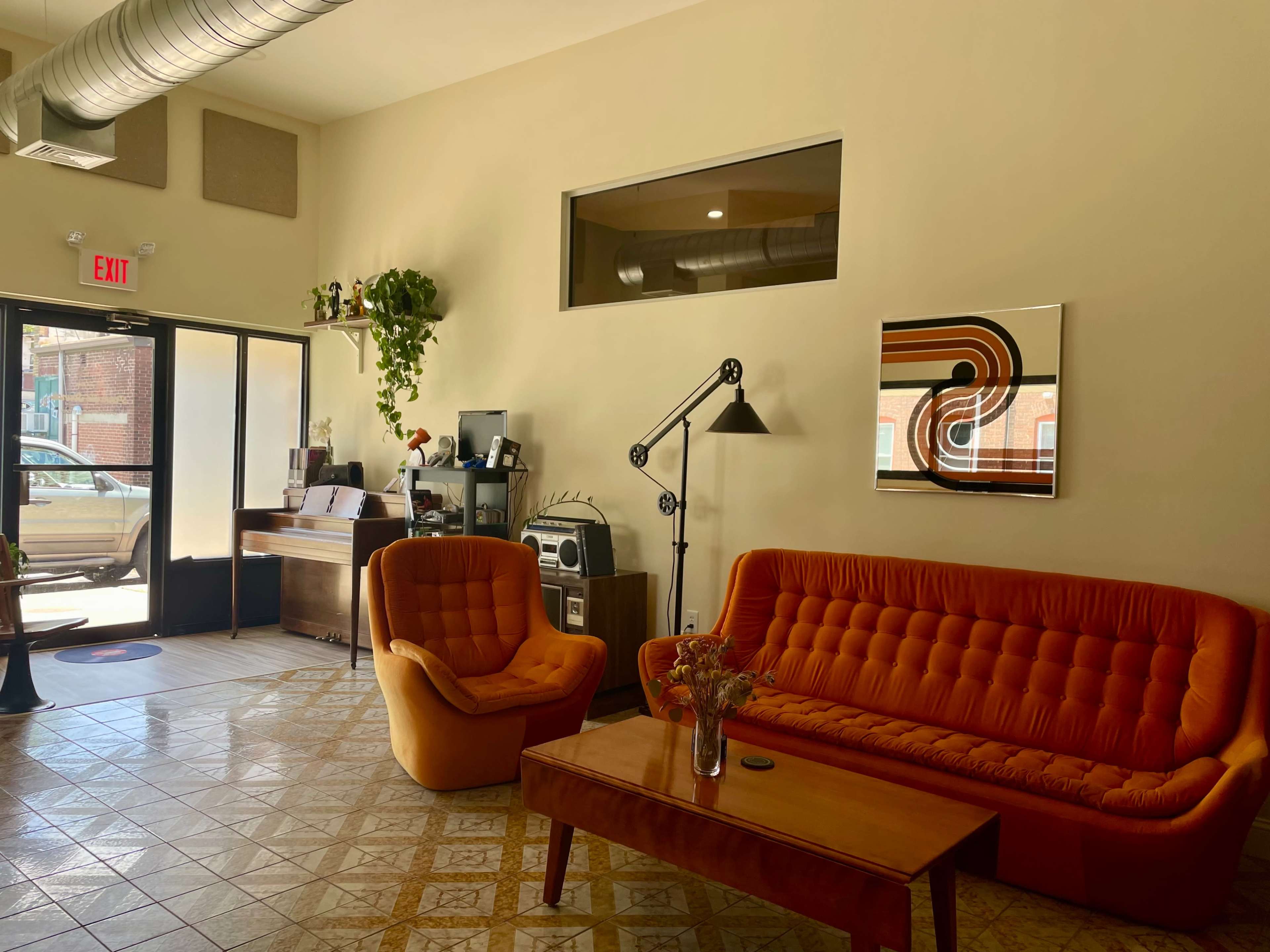 A cozy interior space with orange sofas, a wooden coffee table, and modern decor, including plants and artwork.