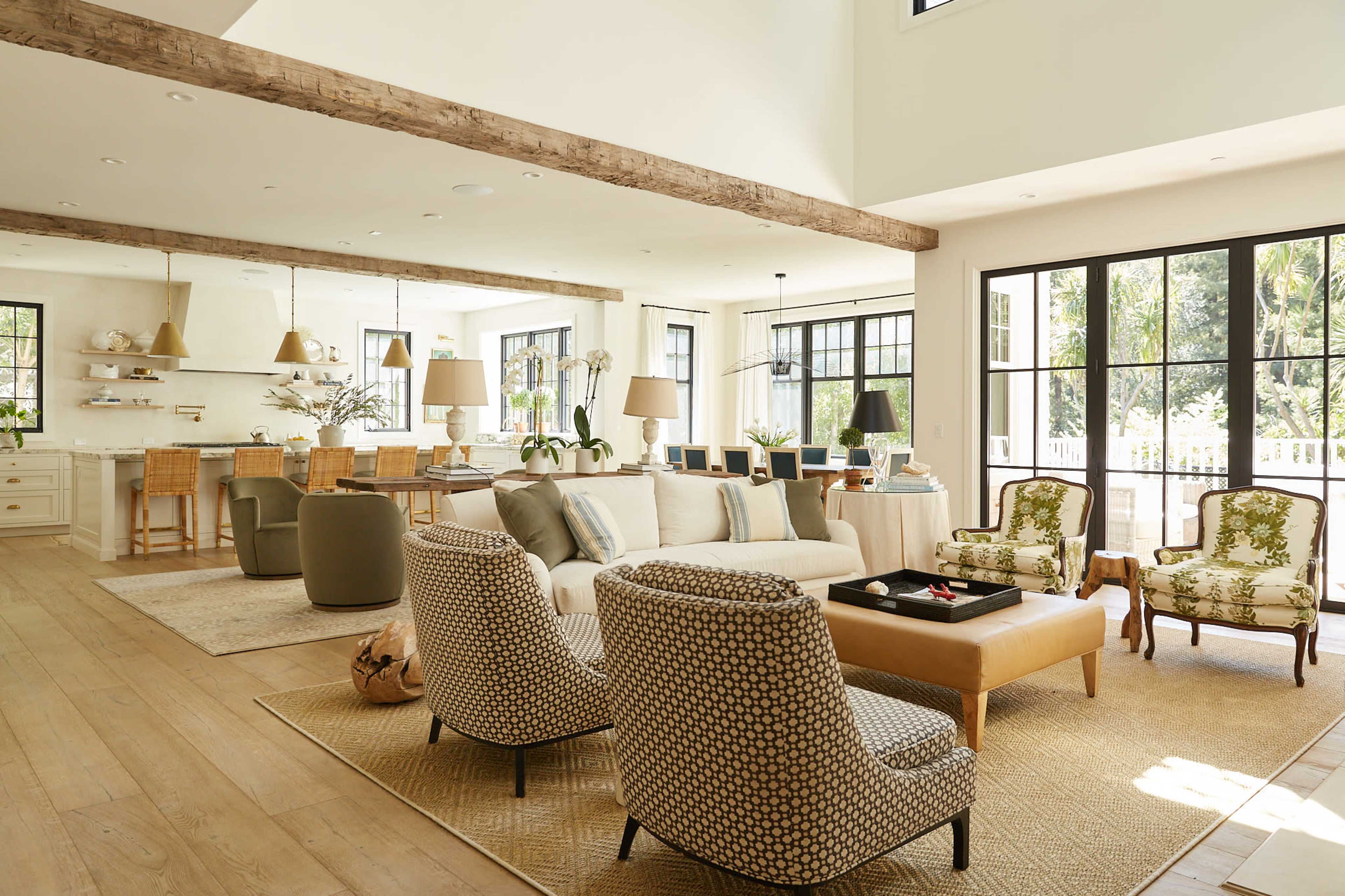 A spacious living area features a mix of modern furniture and natural light, with a large sofa, patterned chairs, and a dining area in the background.