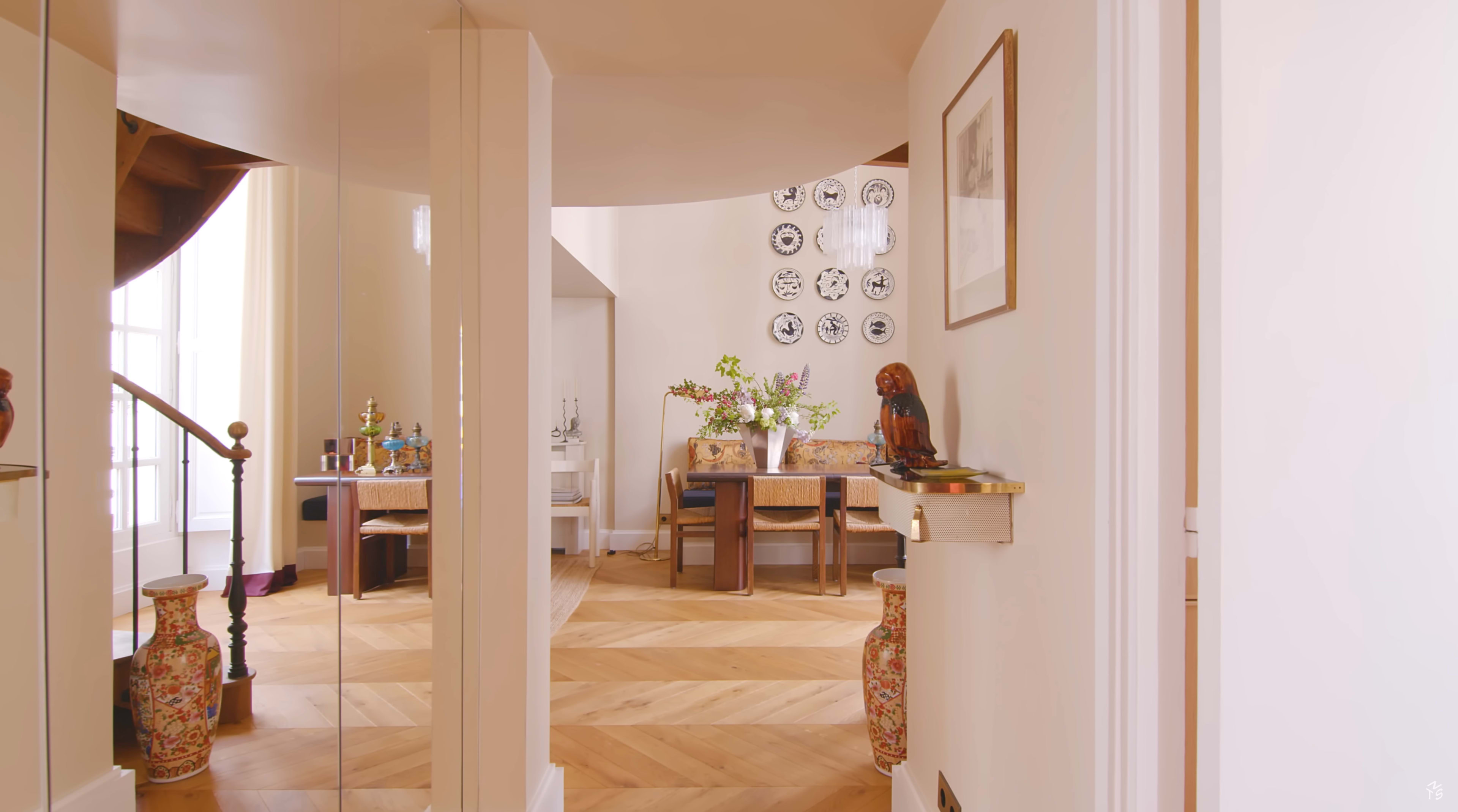 The image shows a well-lit hallway leading to a dining area with wooden furniture and decorative items.