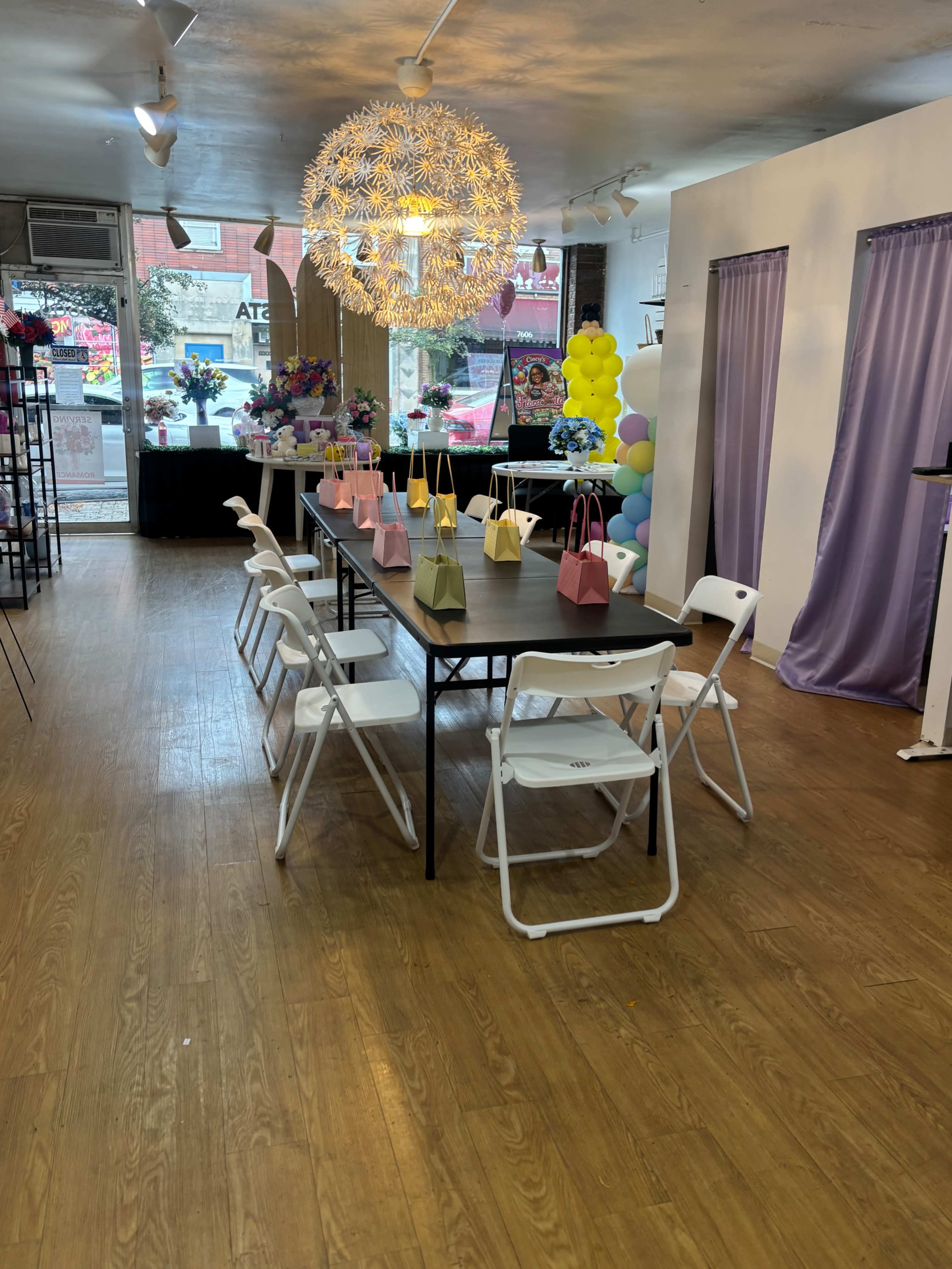 The interior of a decorative space features a long table with chairs arranged around it, surrounded by colorful decorations and a large, unique light fixture.