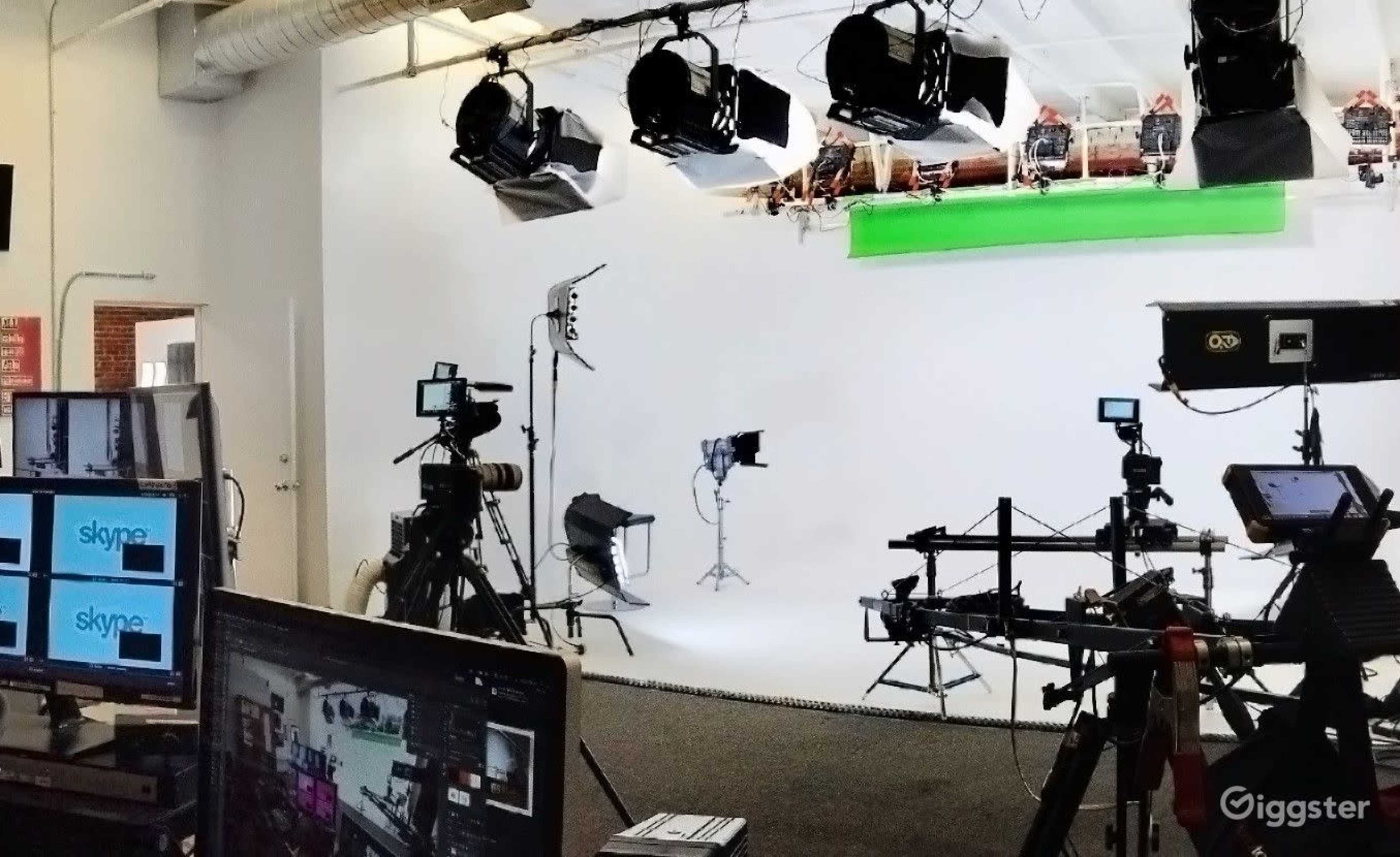 A film studio setup with multiple cameras, lighting equipment, and a blank backdrop.