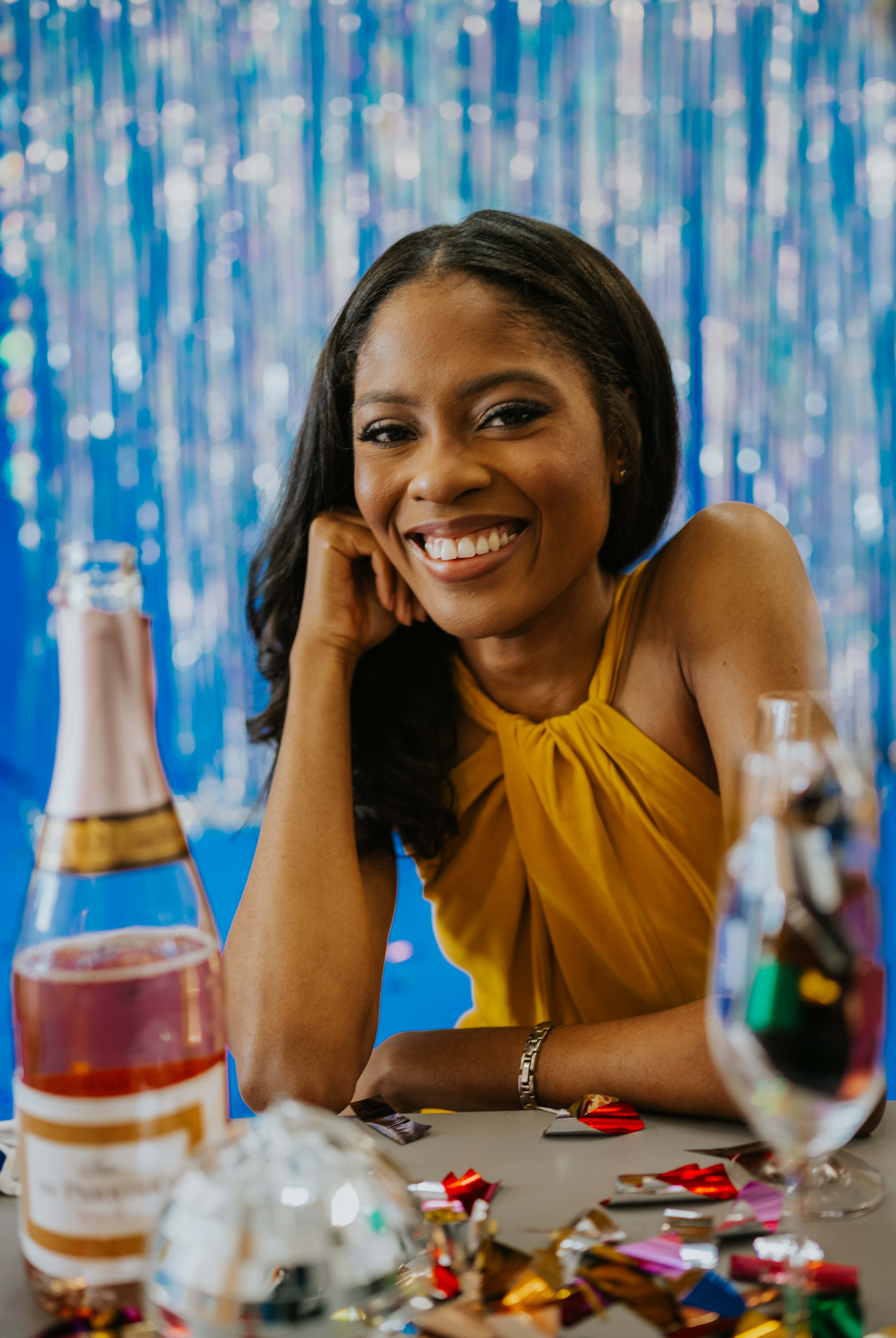 Une femme assise à une table avec une bouteille de vin lors d'un cocktail.