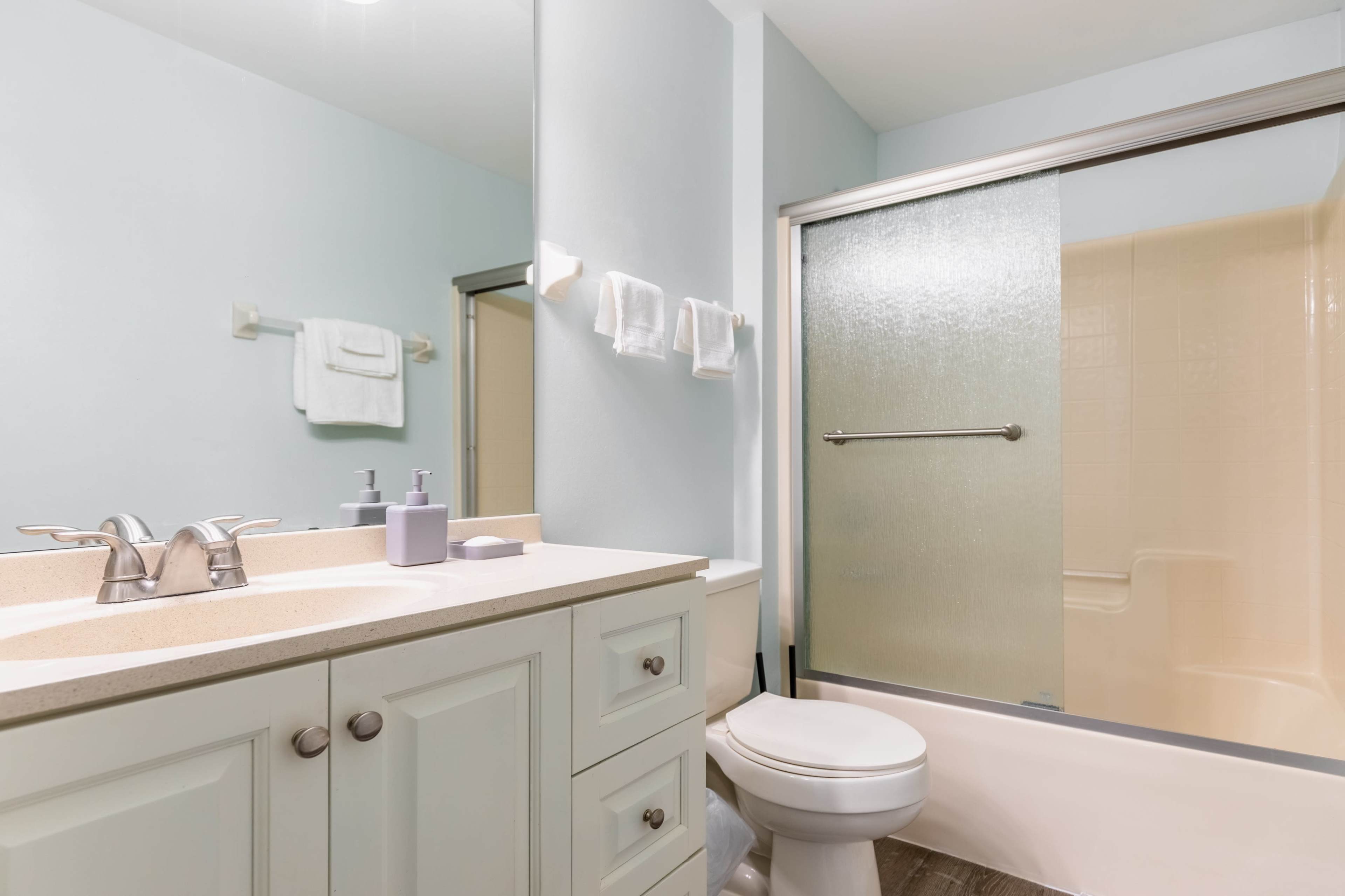 A modern bathroom featuring a sink with a cabinet, a toilet, and a glass shower enclosure.