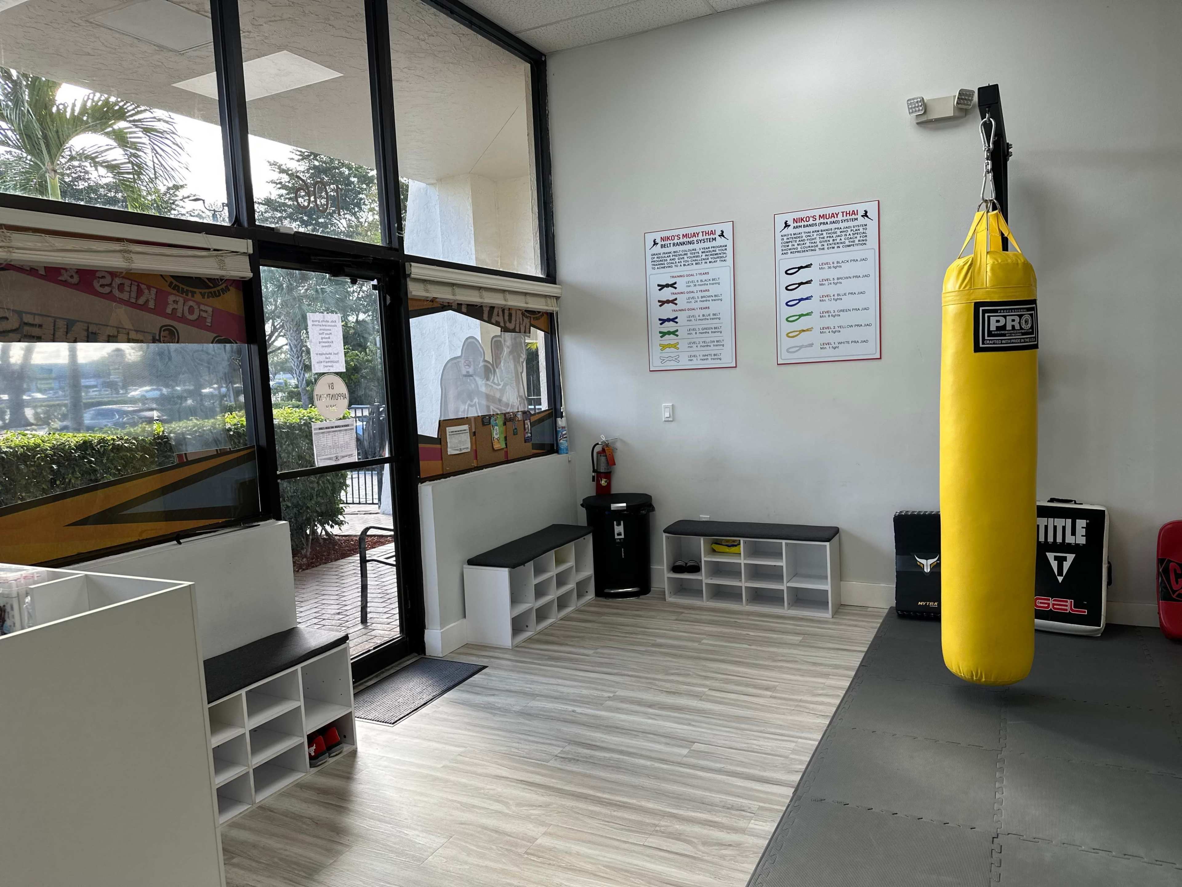 A corner of a gym with a yellow punching bag hanging near seating and informational posters on the wall.