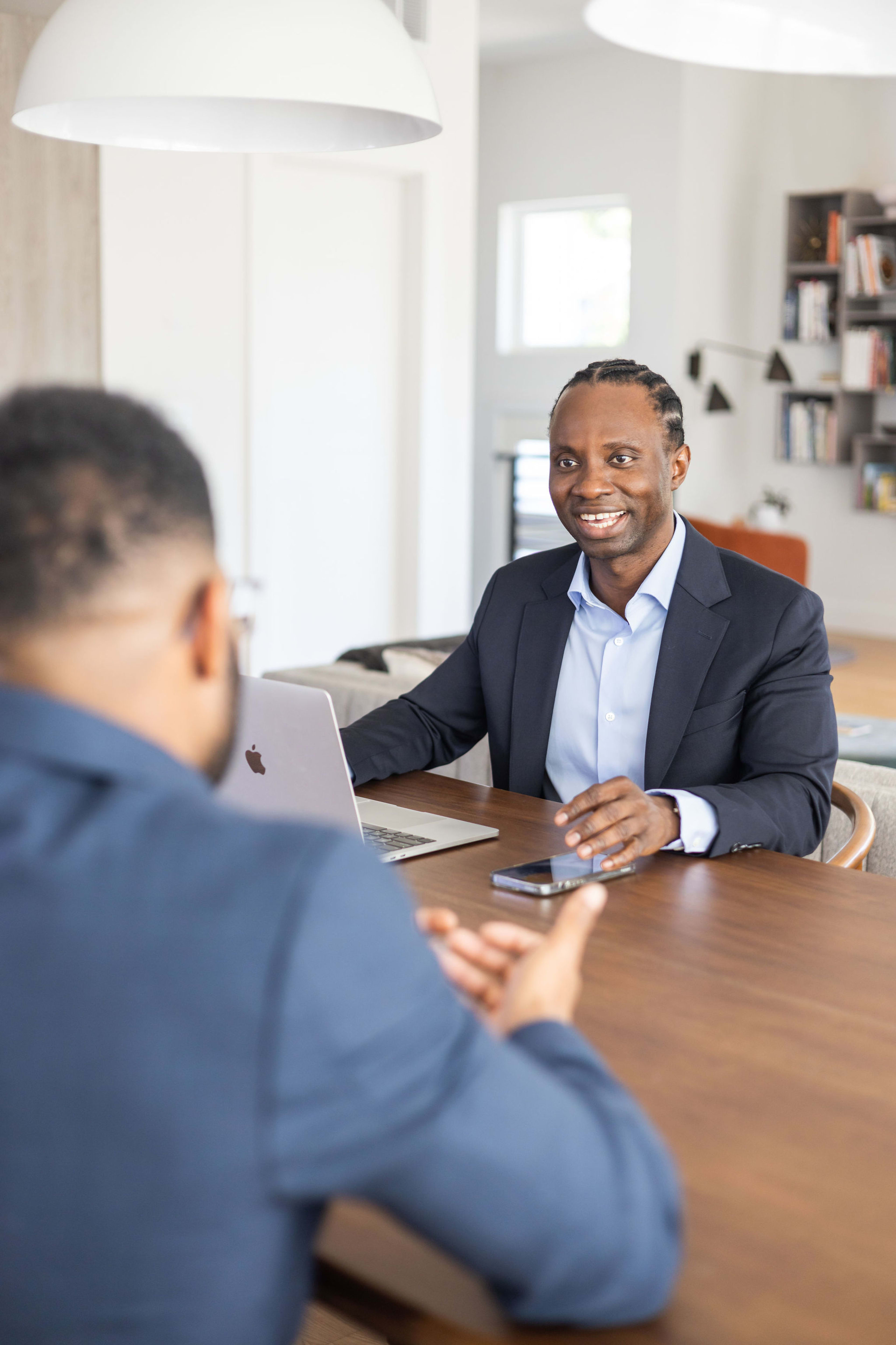 Un homme assis à une table et qui parle à un autre homme.