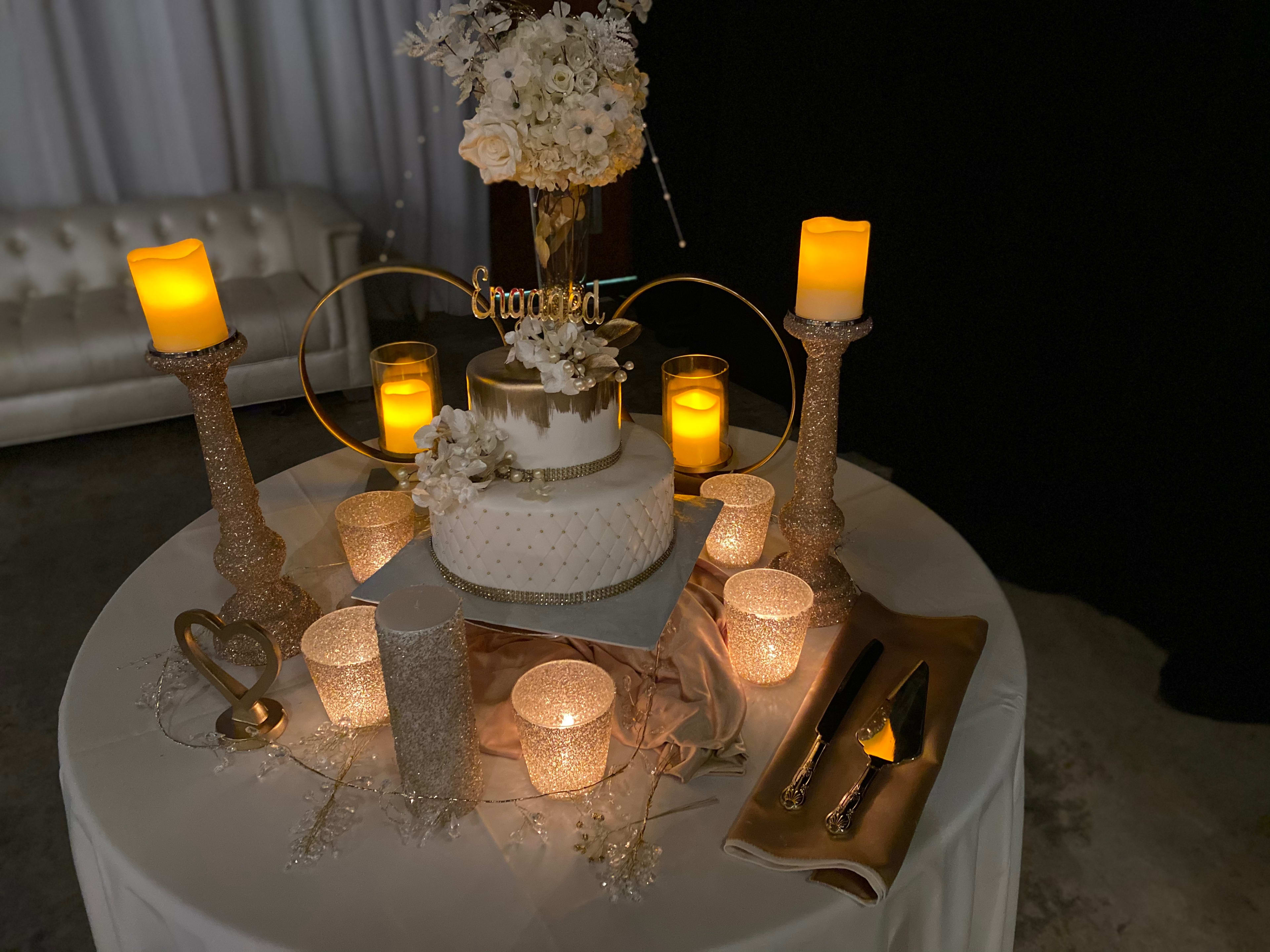 A white cake on a table with lots of candles, perfect for a party or engagement celebration.