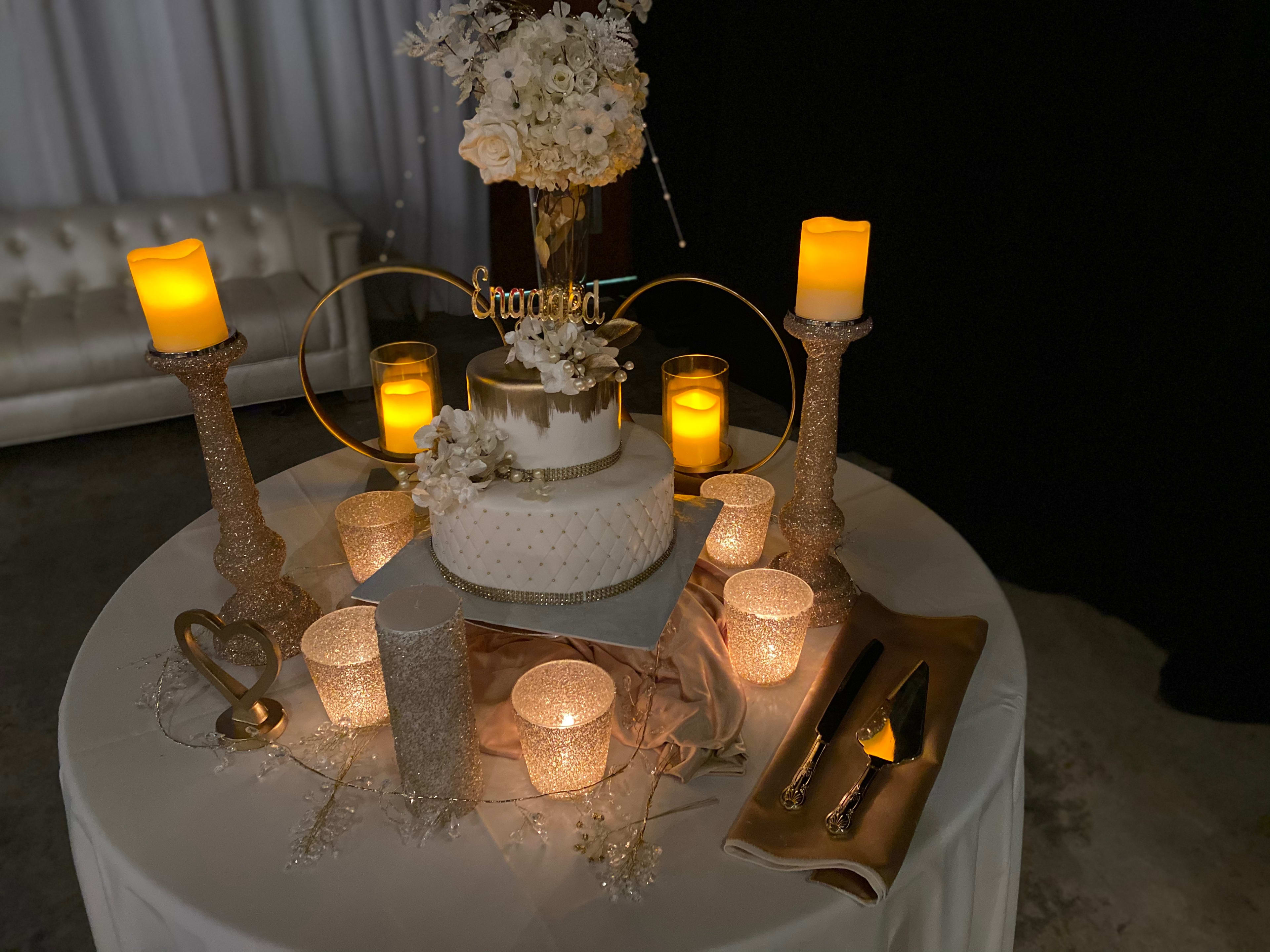 Un gâteau blanc sur une table avec beaucoup de bougies, qui conviendra parfaitement à une fête ou à des fiançailles.