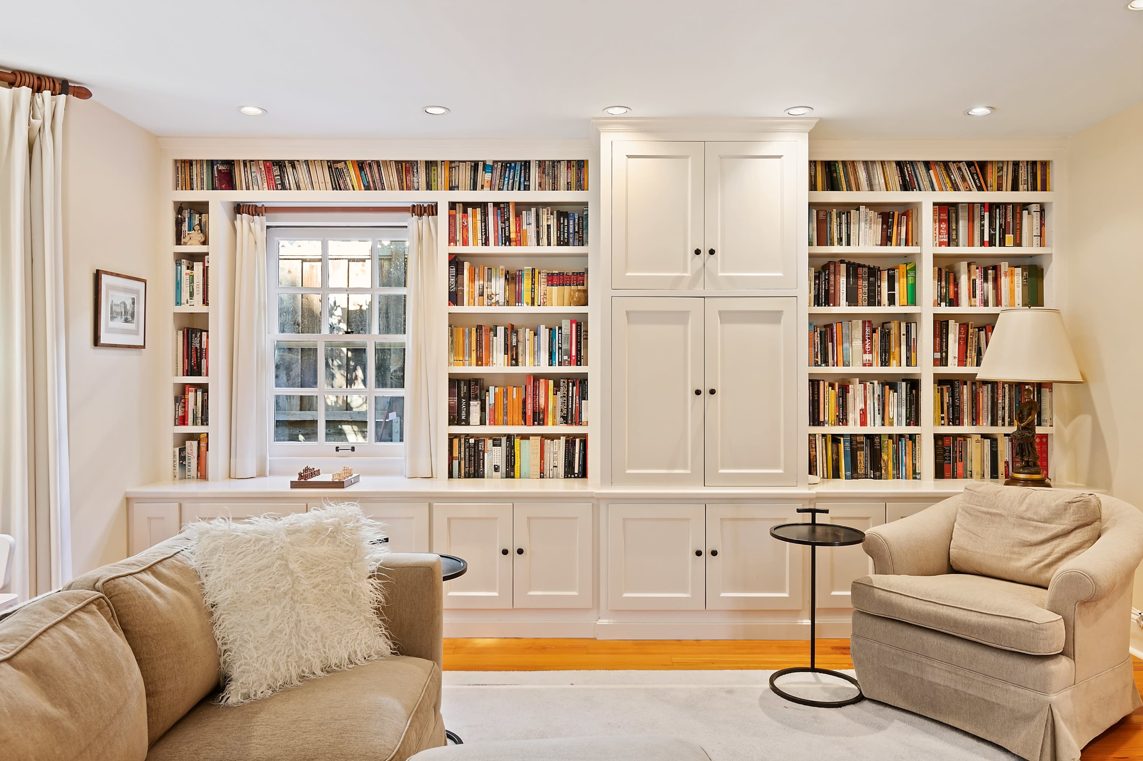 A cozy living room with a large bookshelf filled with books, a comfortable armchair, and a small side table.