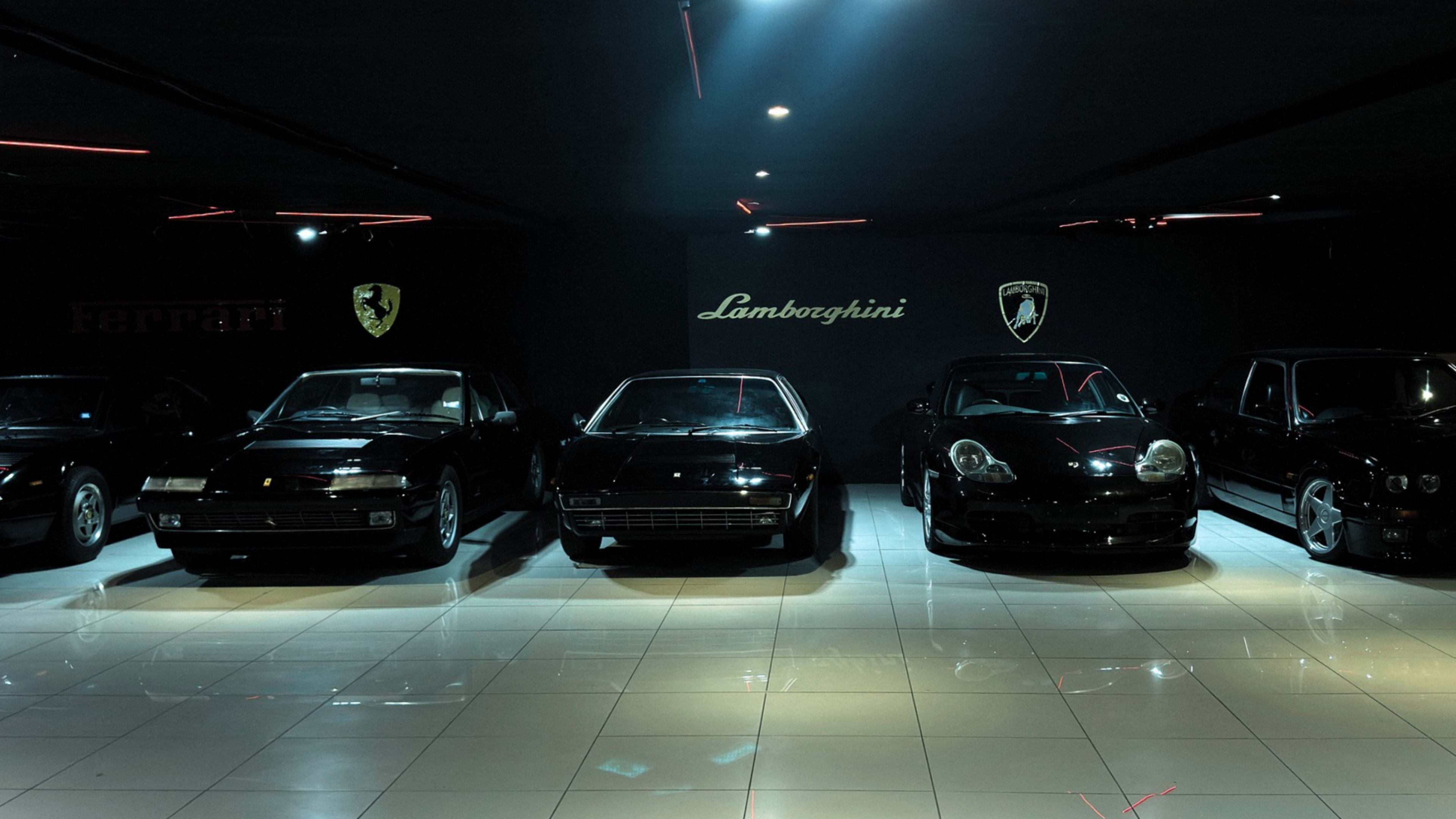 The image features a row of luxury cars, including models from Lamborghini and Ferrari, displayed under dramatic lighting in a dark showroom.
