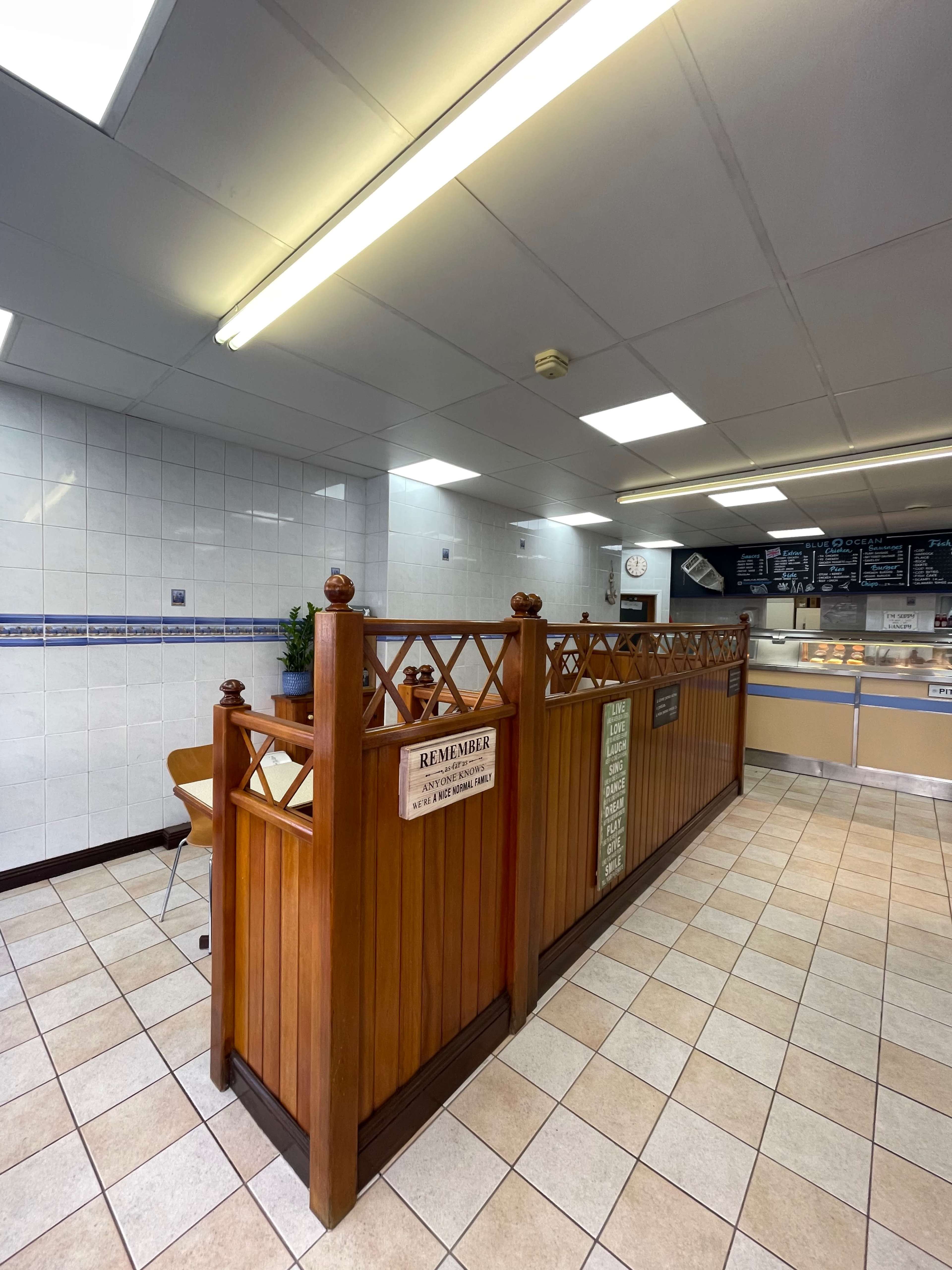 The interior of a food establishment with wooden dividers, tiled flooring, and a service counter in the background.