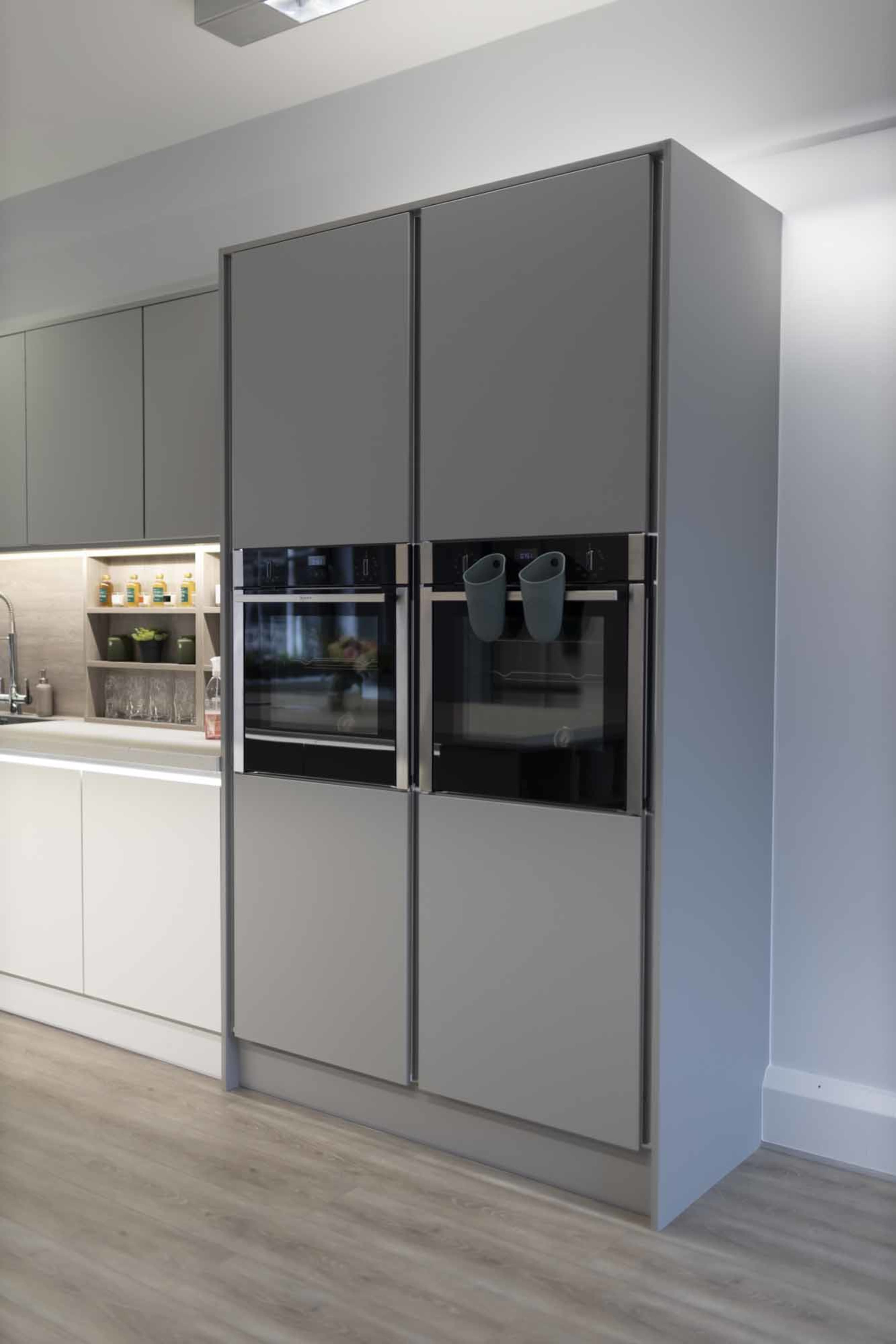 A modern kitchen with a large, gray double-door refrigerator and built-in ovens, set against a light-colored cabinetry backdrop.