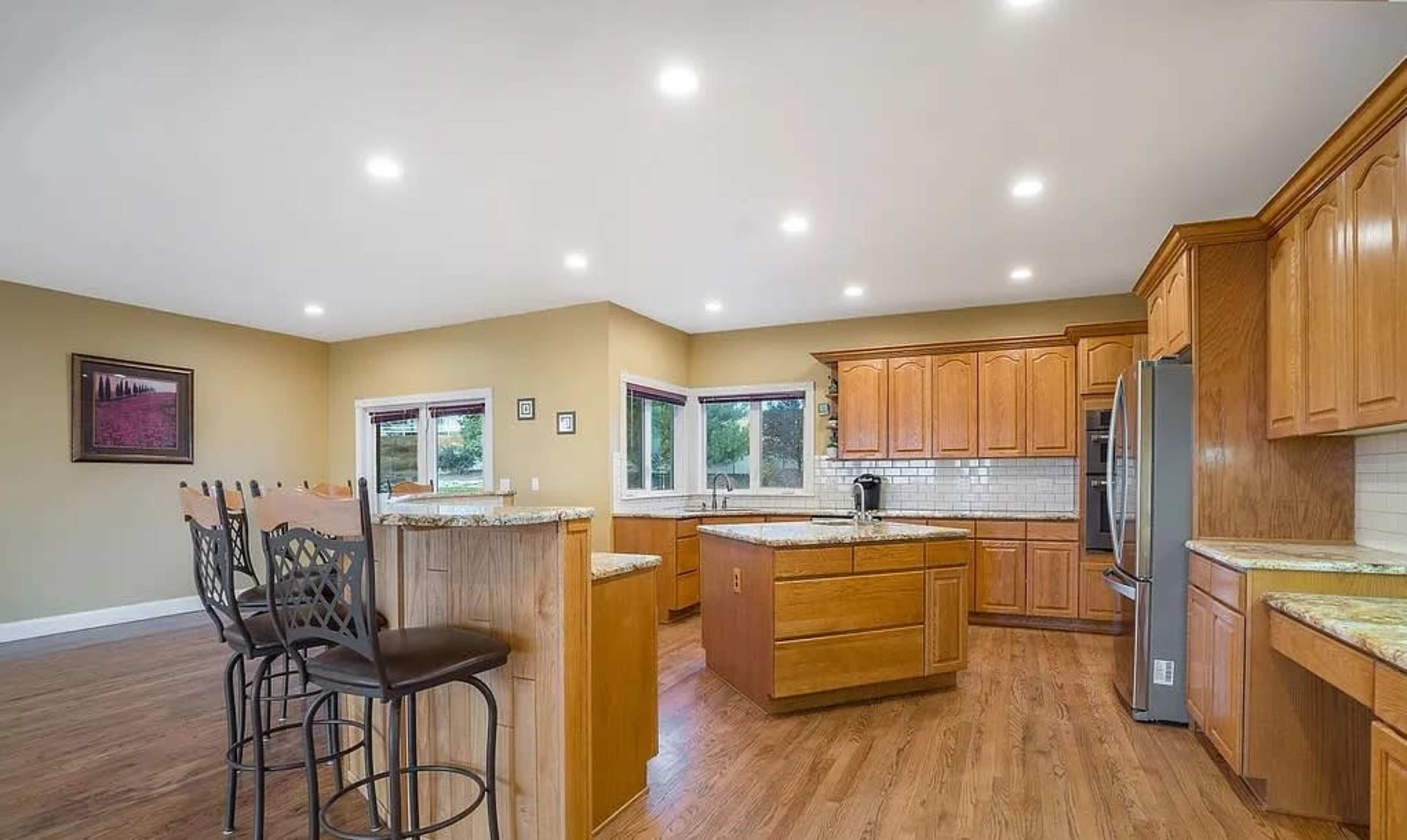 A spacious kitchen features wooden cabinetry, a central island, and bar seating.