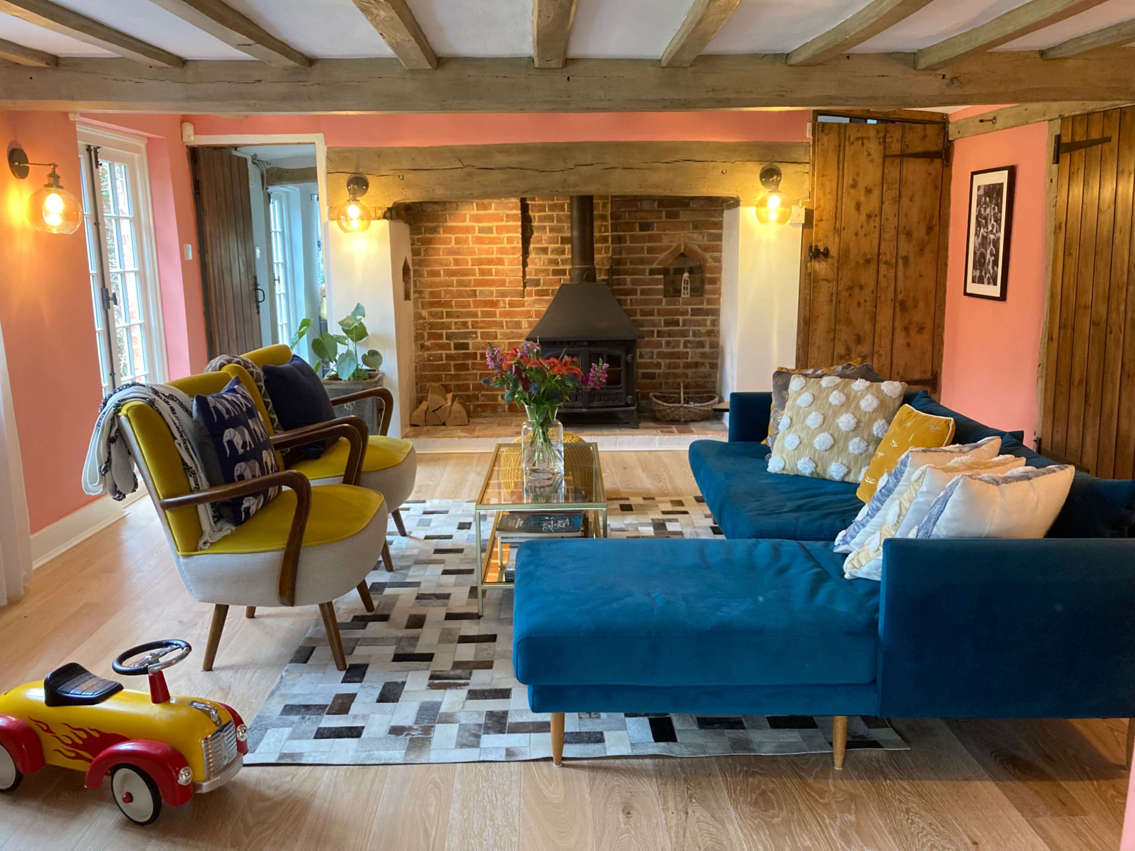 A cozy living room with a blue sectional sofa, a yellow accent chair, a coffee table, and a brick fireplace in the foreground.