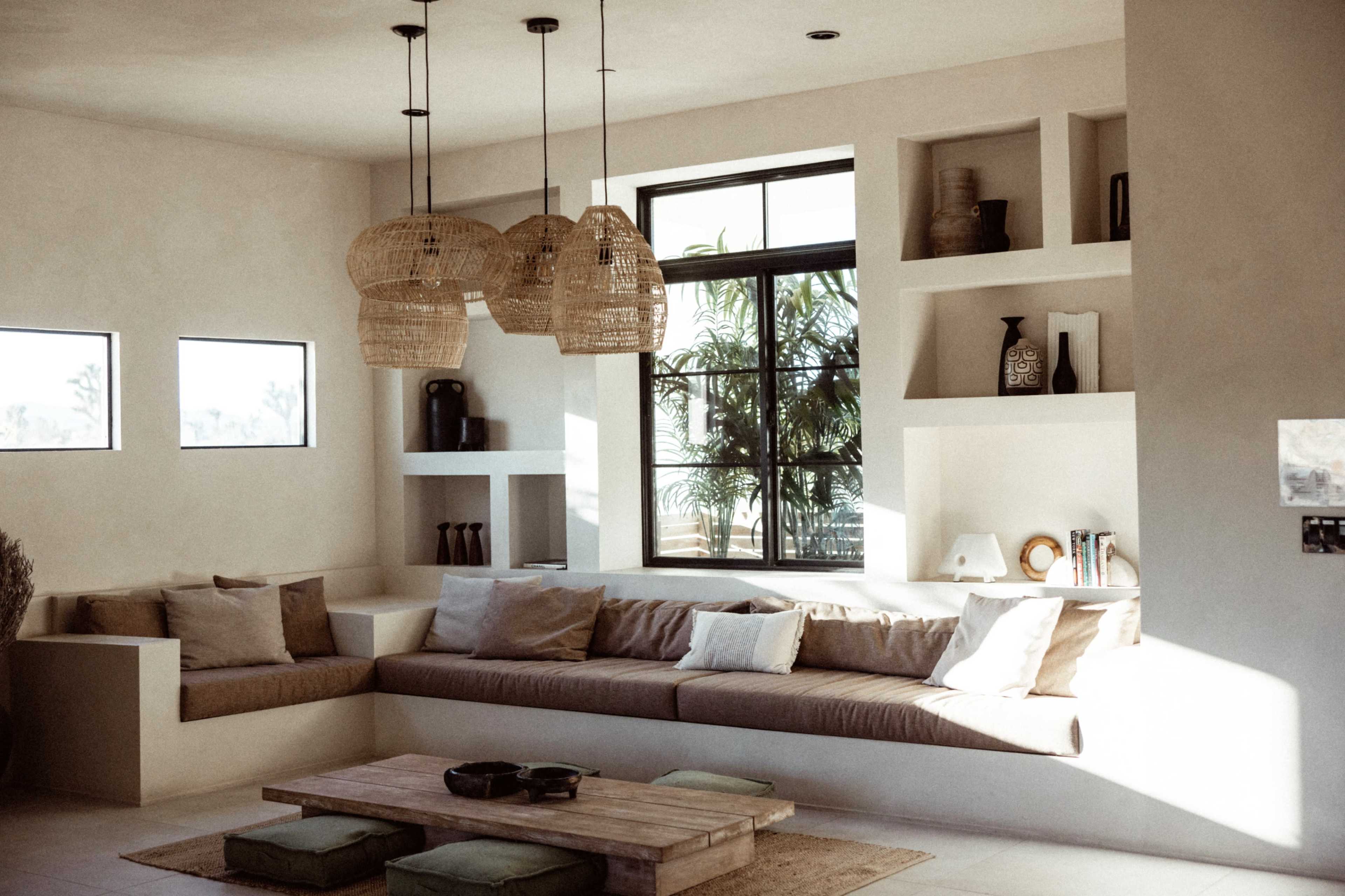 A modern living room featuring a large, L-shaped sofa with decorative pillows, a wooden coffee table, and three pendant lights hanging from the ceiling.
