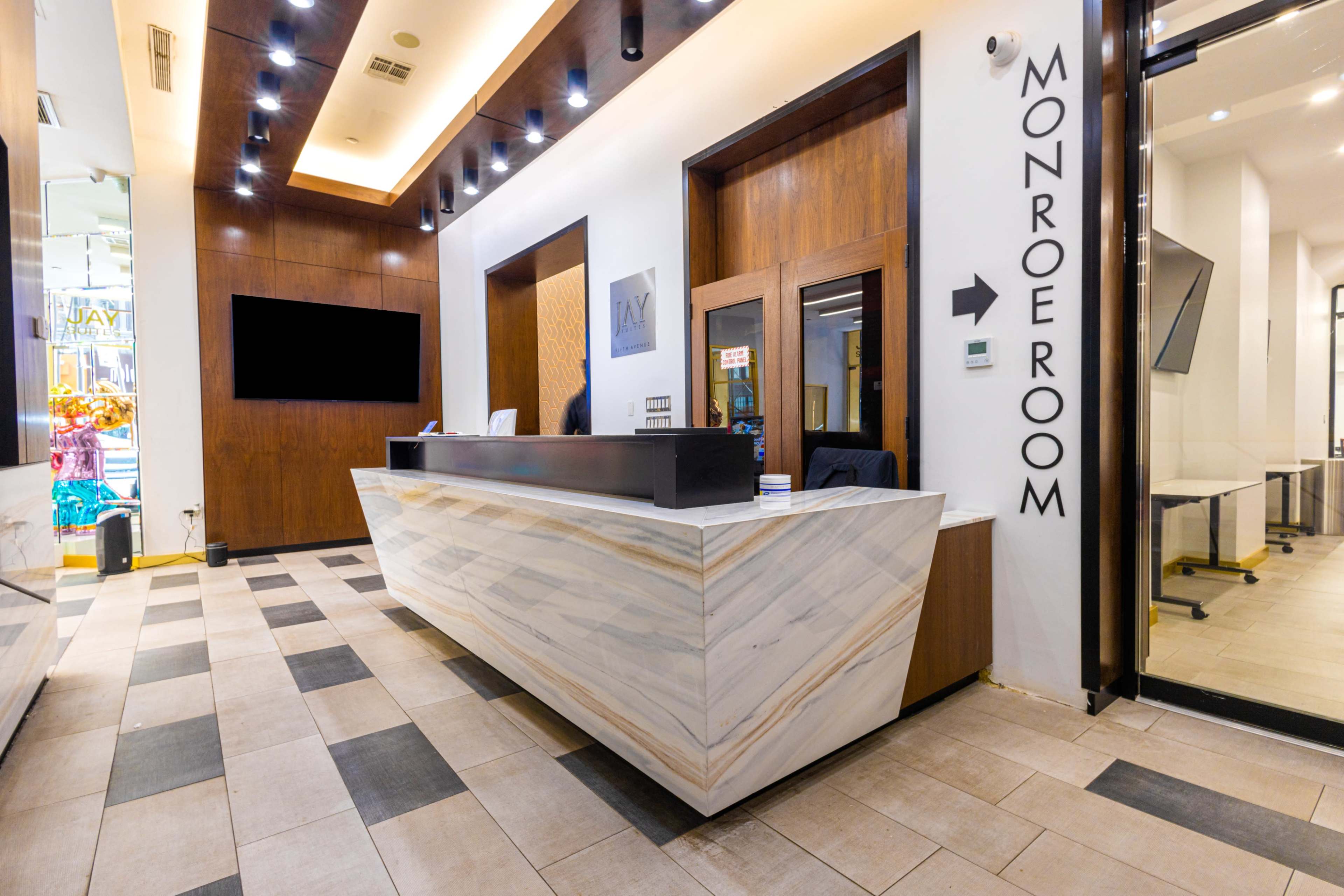 A modern reception area featuring a marble front desk and a sign directing to the "Monroe Room."