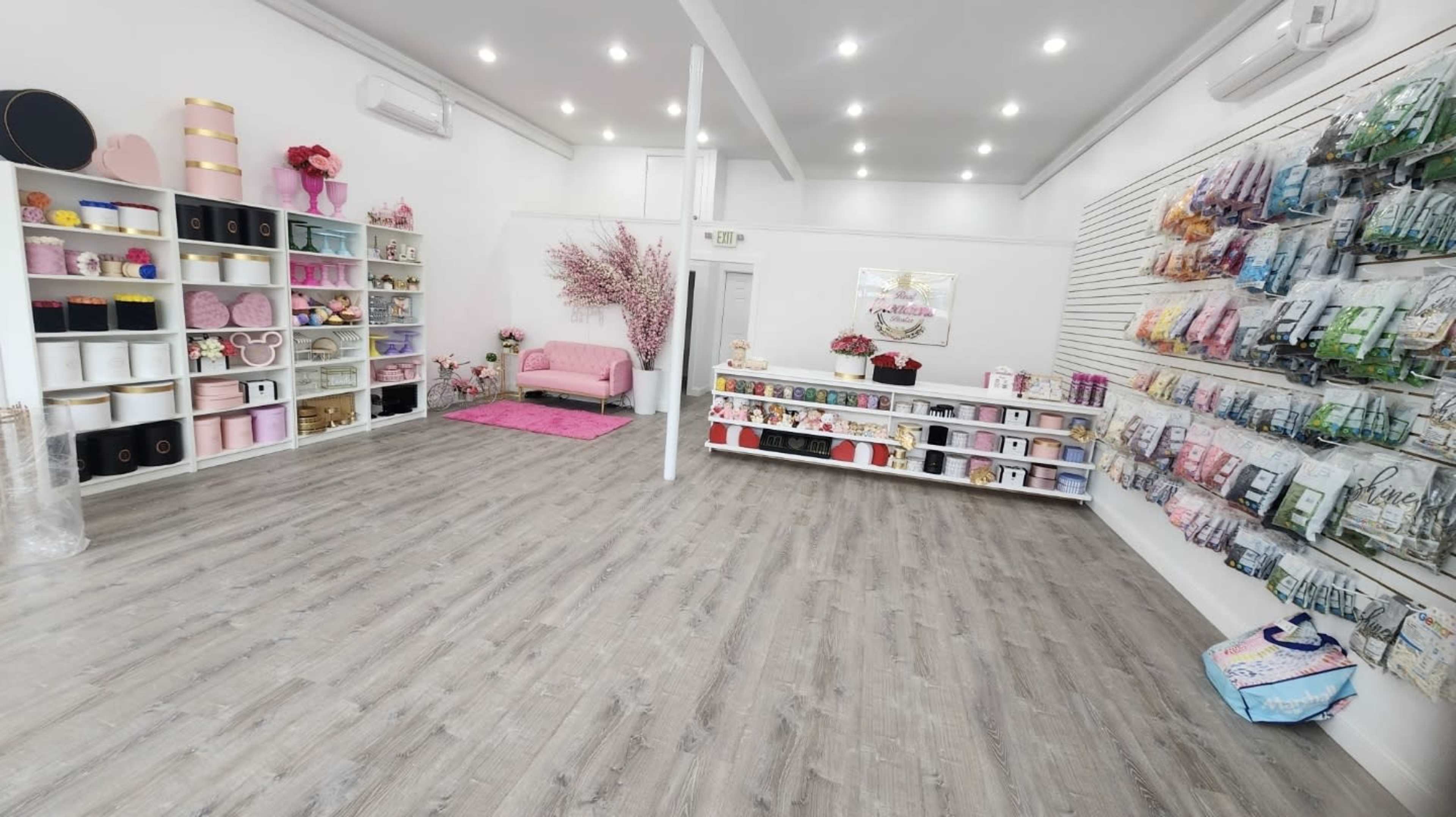 A well-lit retail space featuring shelves filled with decorative items and a pink upholstered chair in the center.