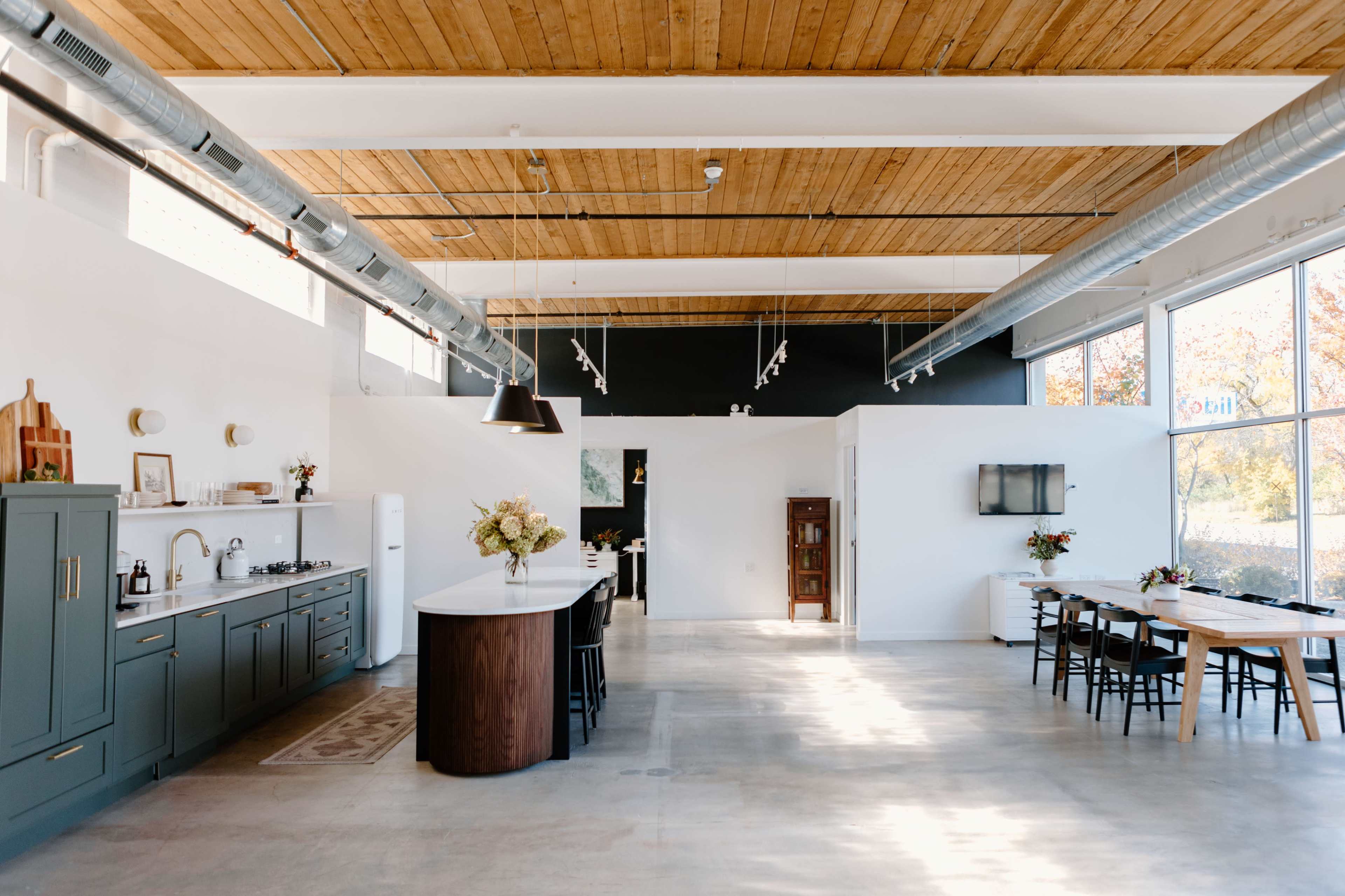 A spacious kitchen and dining area with a large island, modern cabinetry, and a minimalist design featuring large windows.