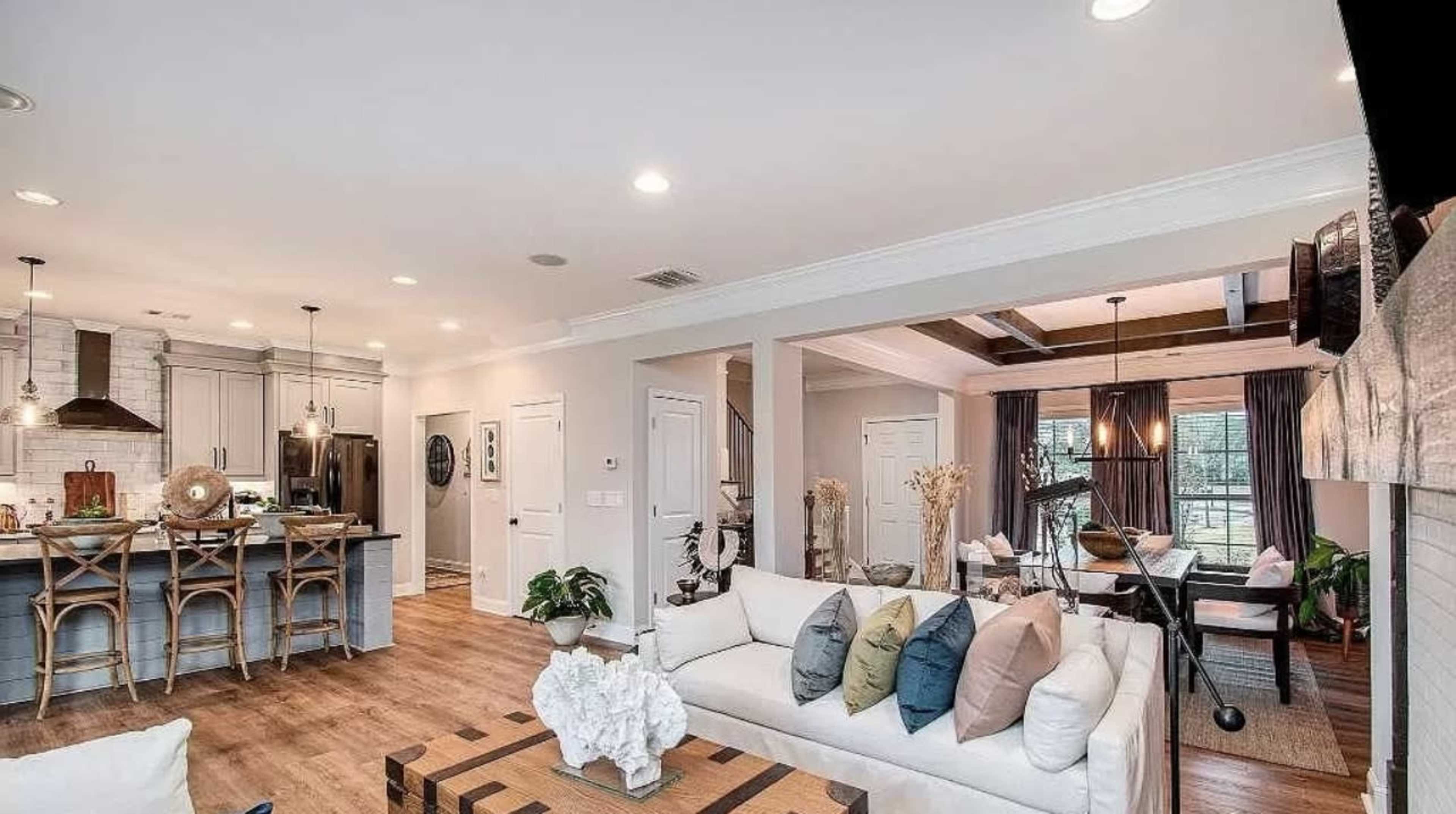 A modern open-concept living area that includes a kitchen, dining space, and a sitting area with a sofa and decorative pillows.