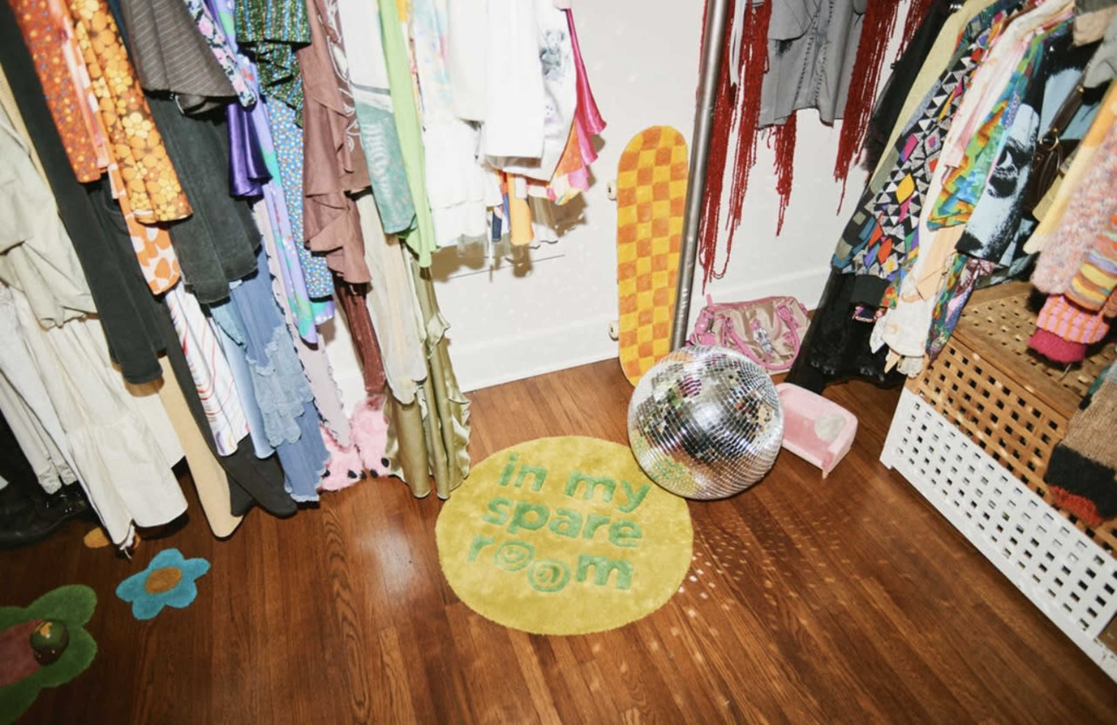 A colorful closet features a patterned rug that reads "in my spare room" and a disco ball sitting on wooden flooring.