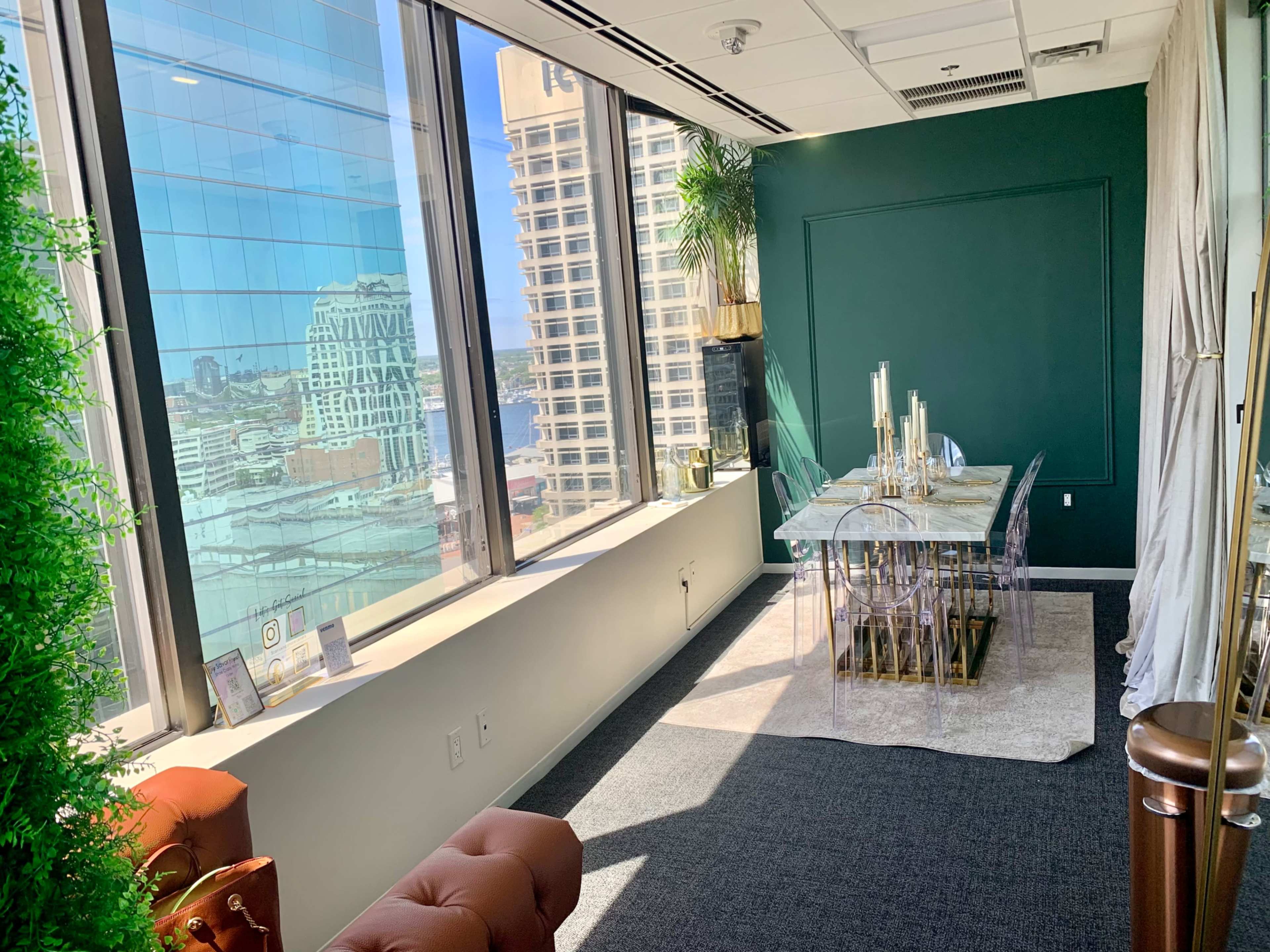 A modern conference room with a glass dining table and illuminated candles, surrounded by large windows offering a view of a cityscape.