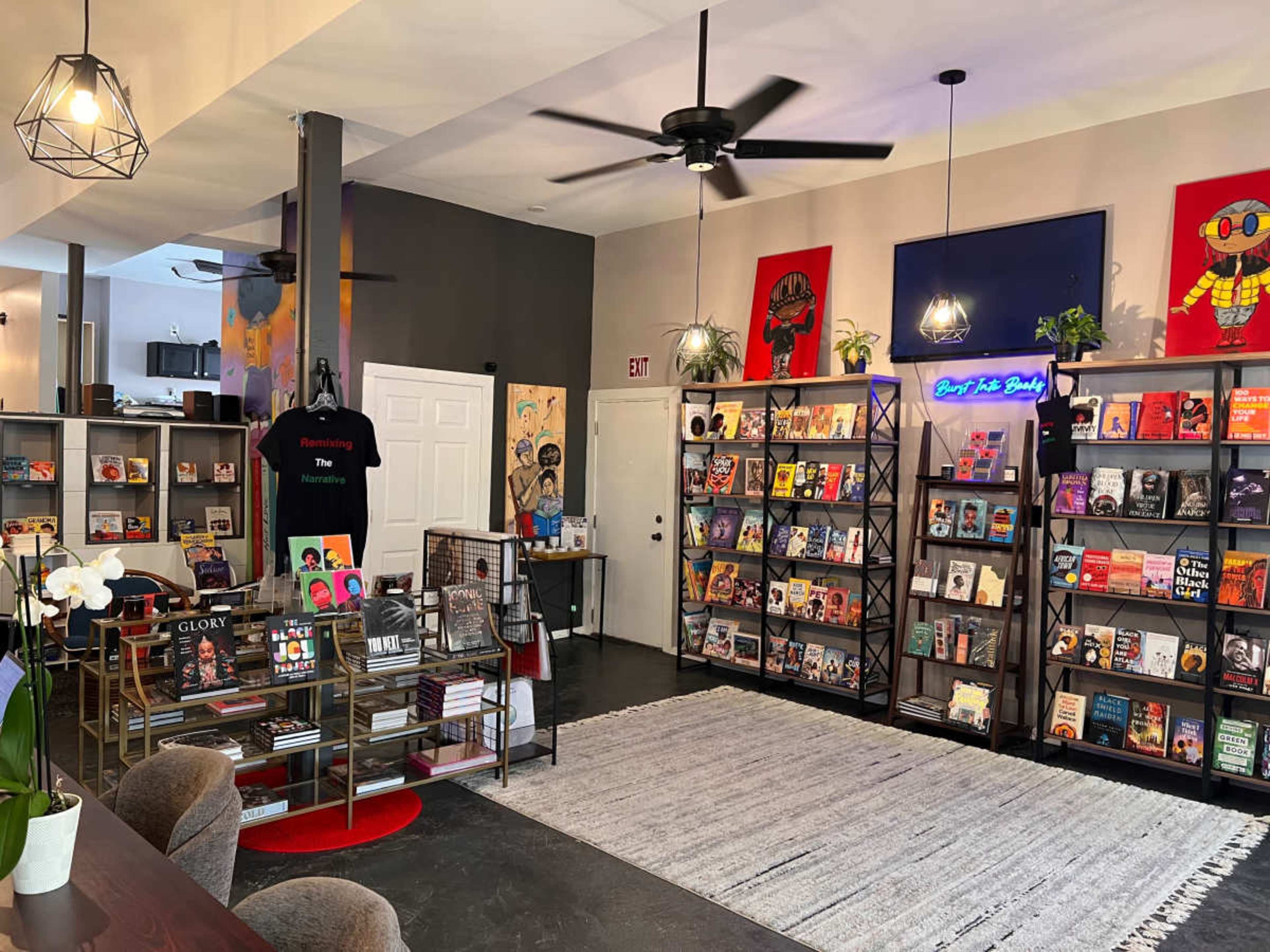 The image shows a cozy bookstore featuring shelves filled with various books, seating areas, and colorful artwork on the walls.