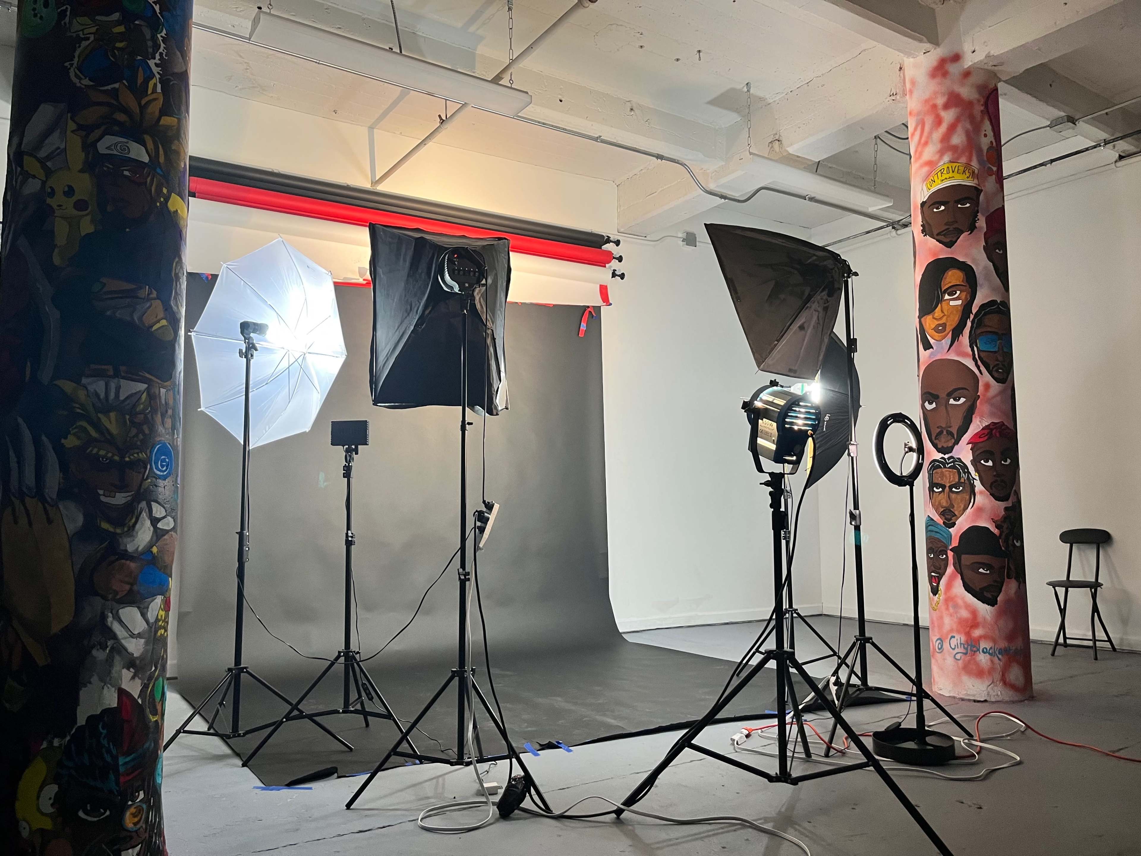 A photography studio set up with multiple lights, backdrops, and painted columns.