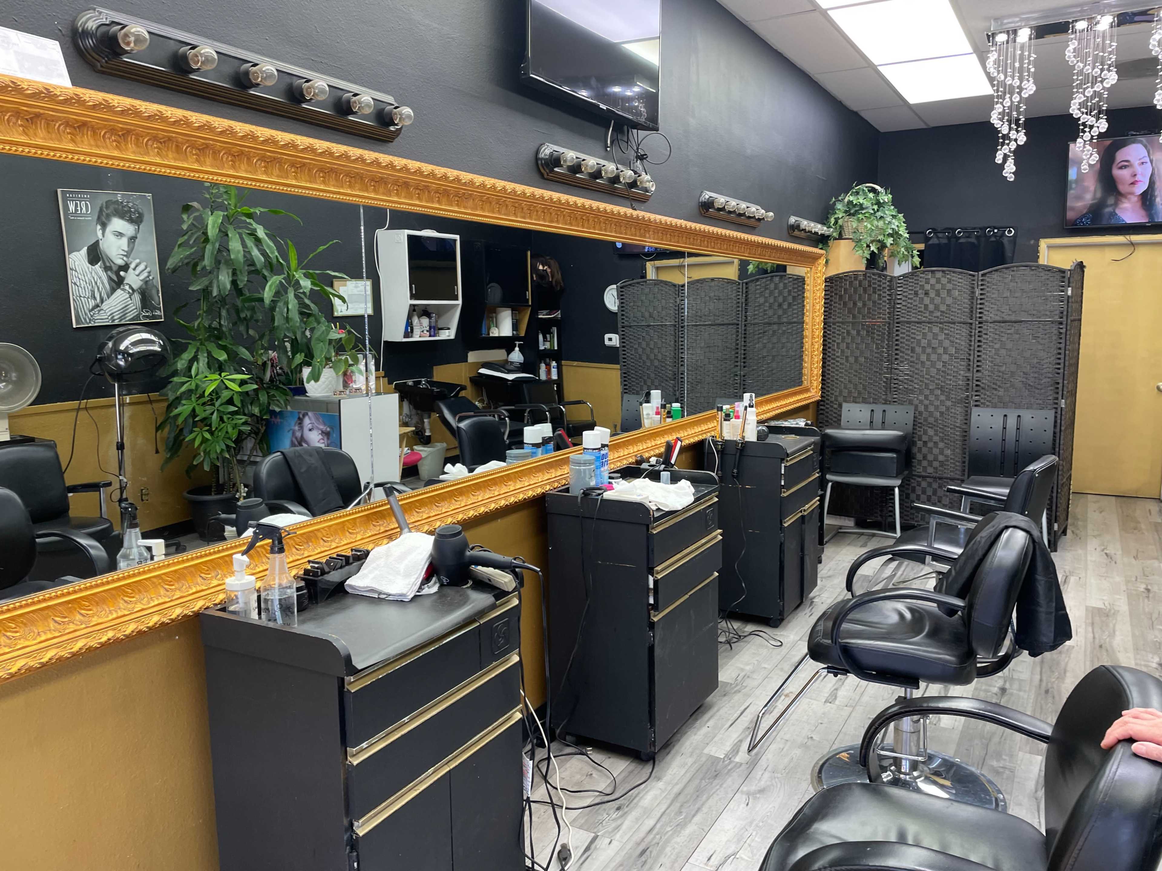 A hair salon with a large mirrored wall, several styling chairs, and a partition for privacy, surrounded by salon equipment and decorative elements.