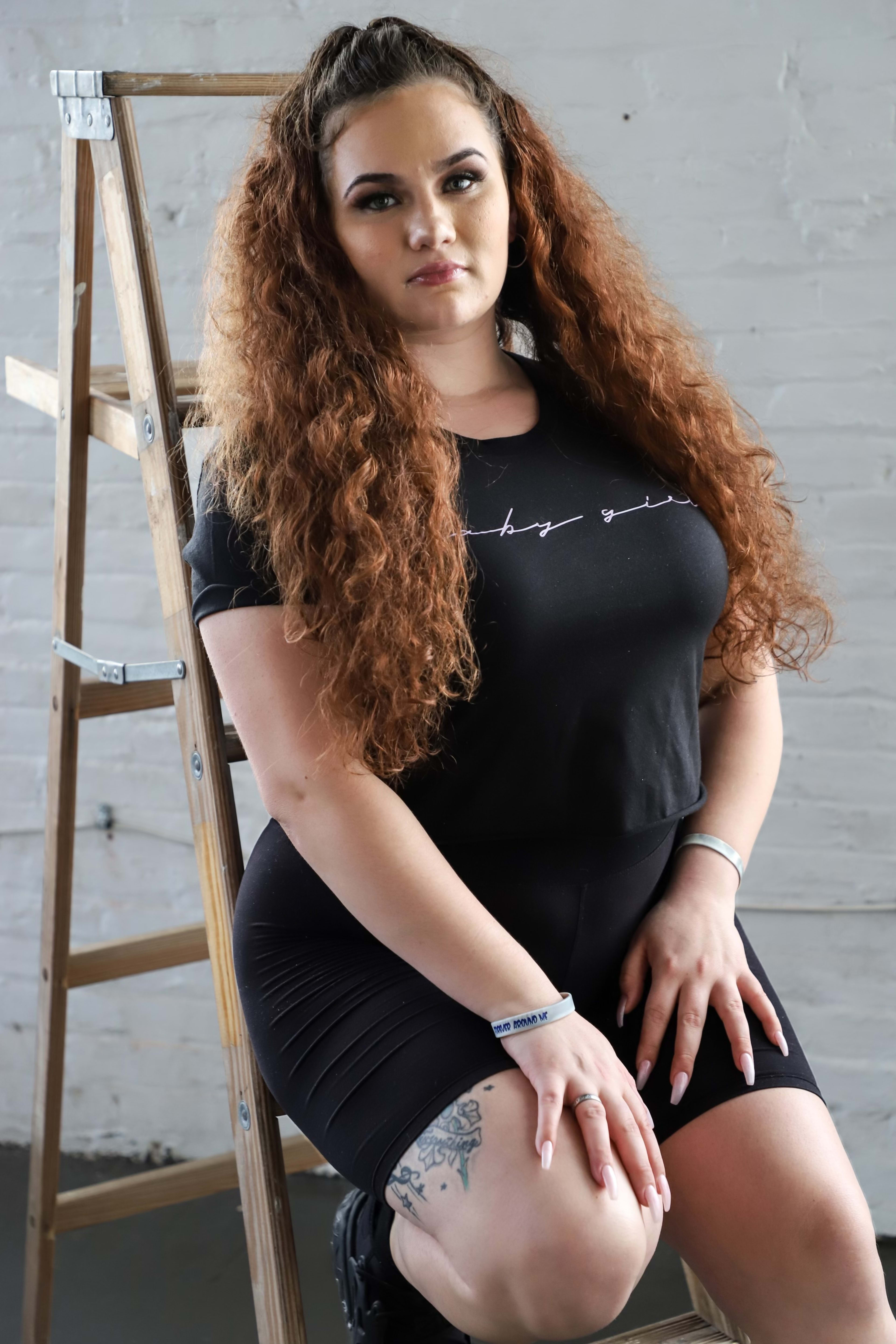 A woman posing for a portrait on a step ladder during a photoshoot.