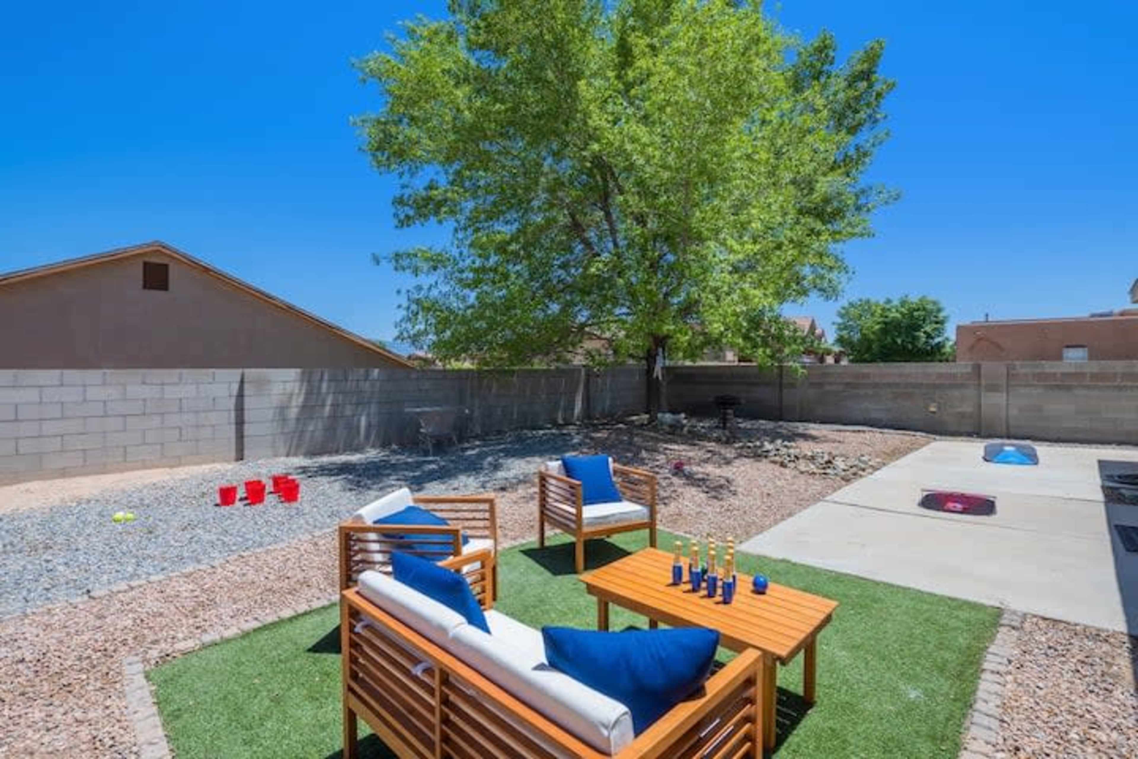 A backyard with two wooden seating areas, a large tree, and a gravel-covered section.