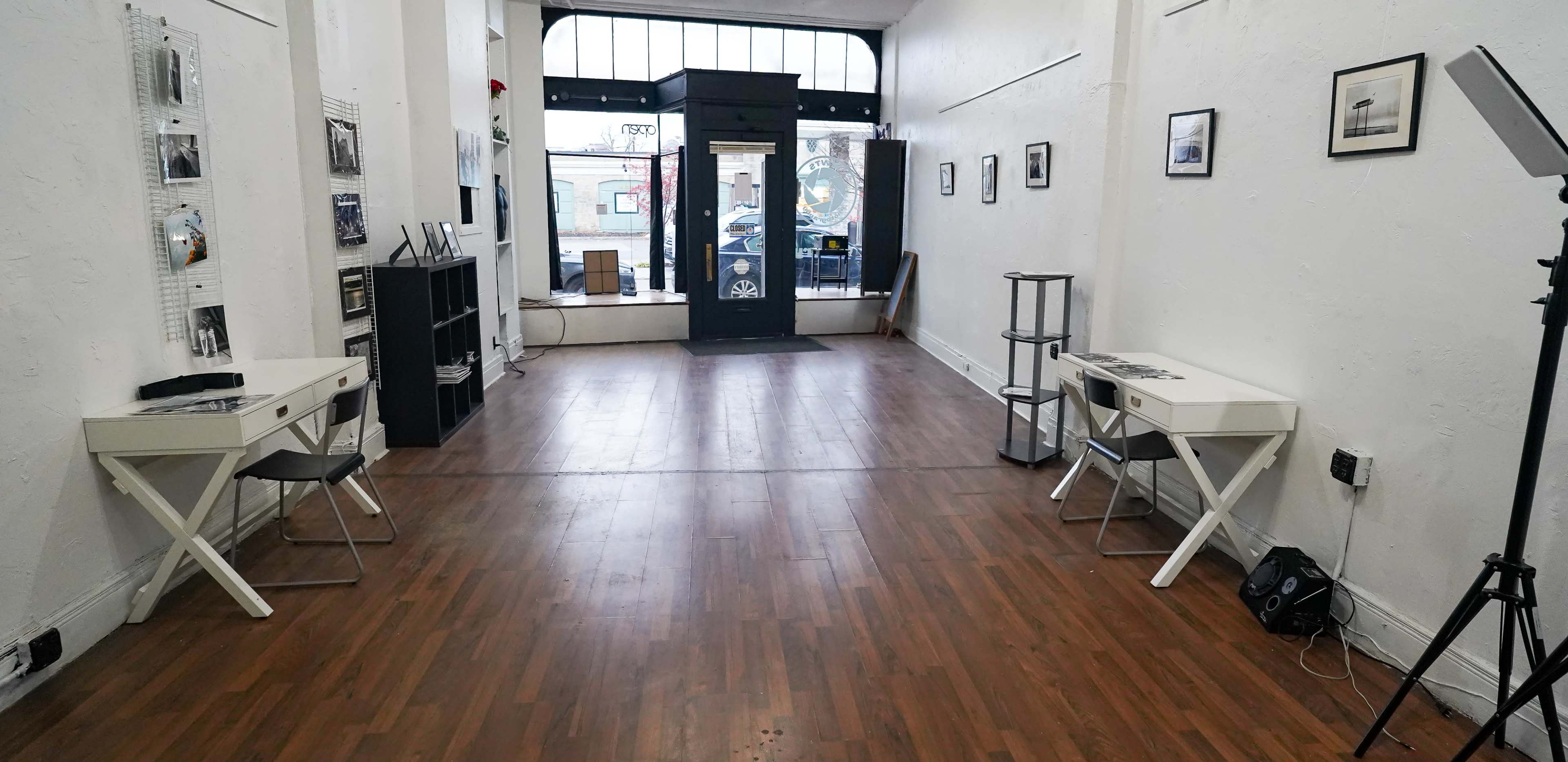 A spacious, modern interior of an empty gallery with two white desks on either side and a large entrance at the end.
