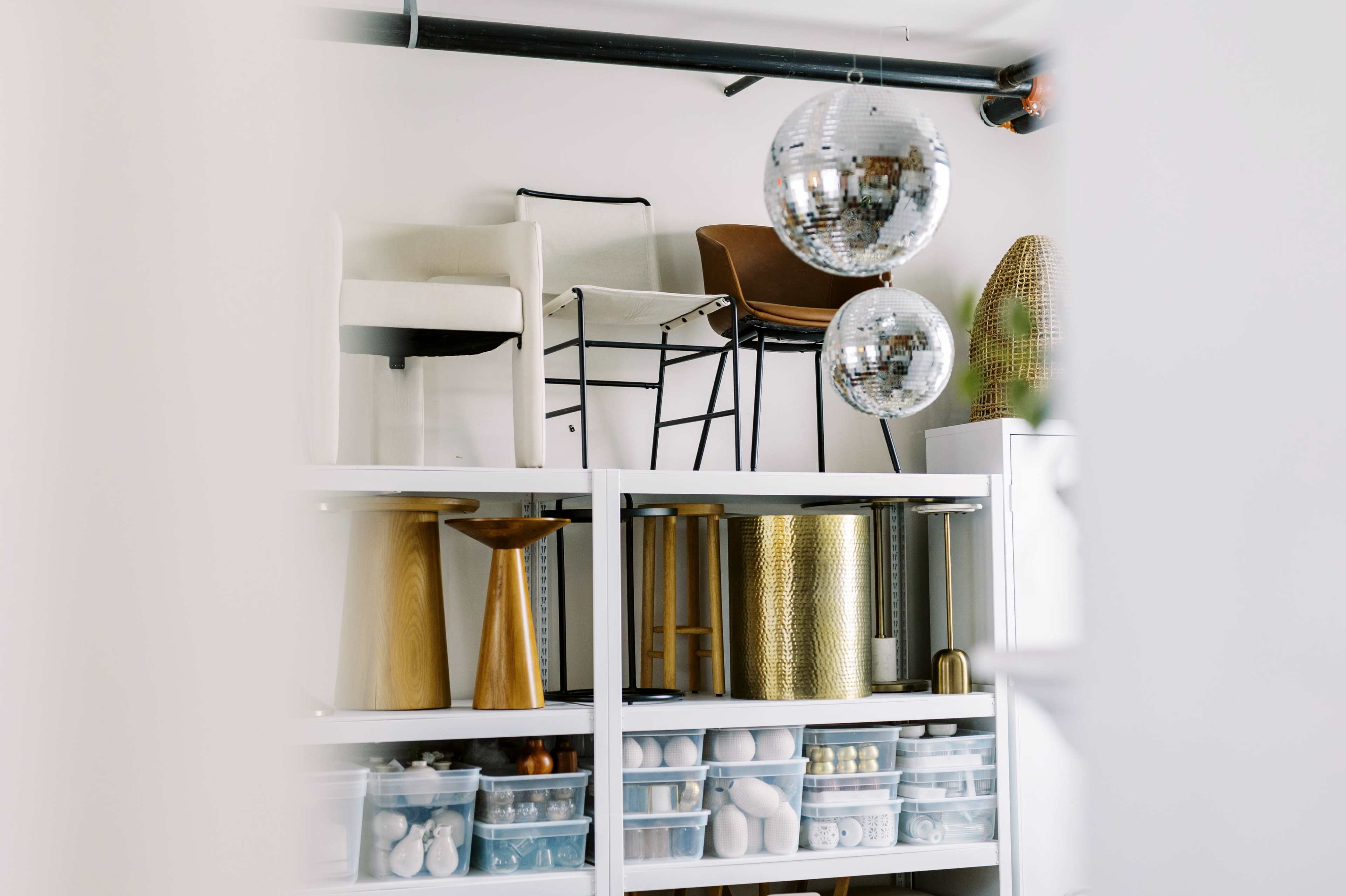 The image shows a modern storage area with shelves holding various decorative items and two disco balls hanging from the ceiling.