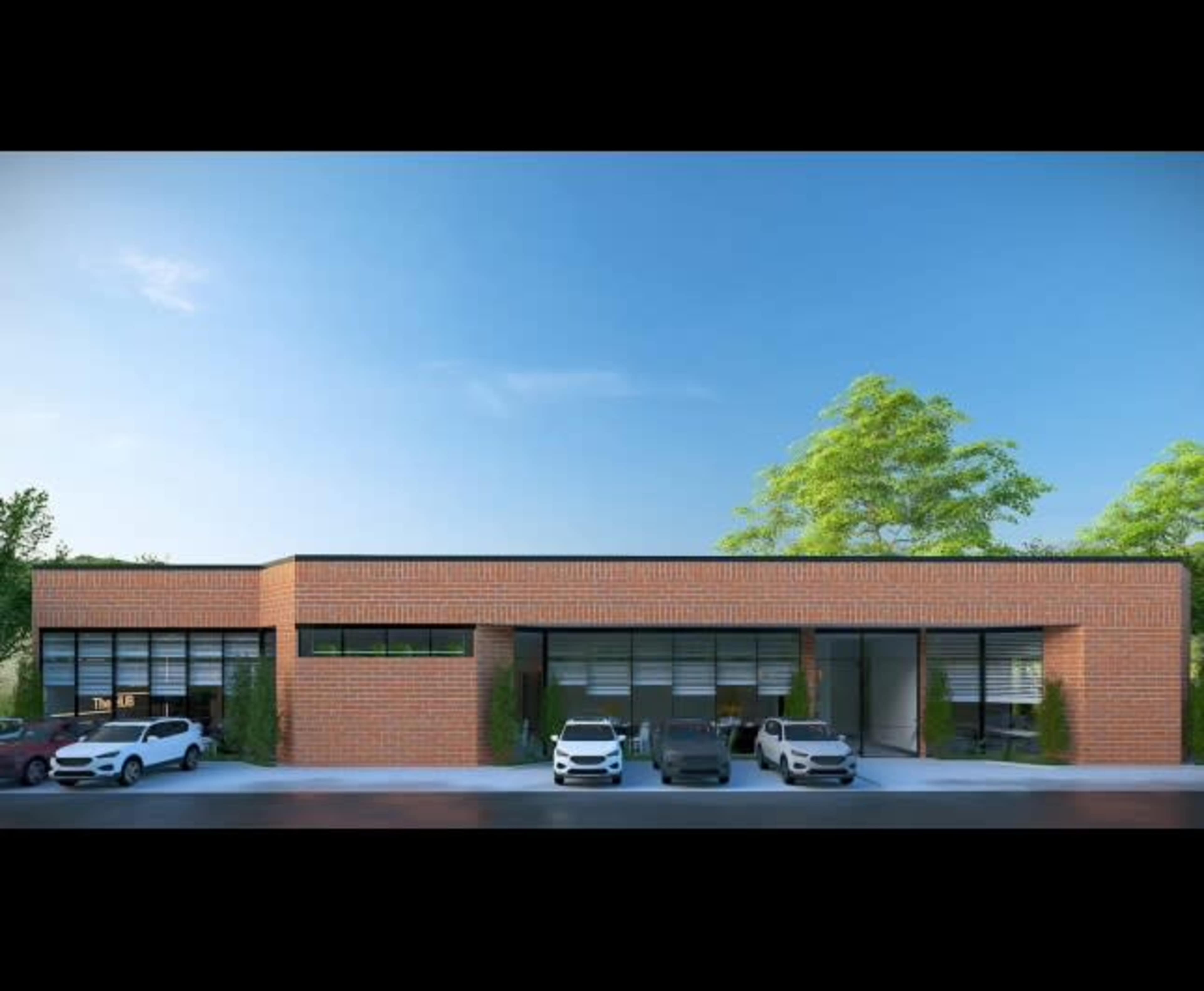 The image shows a modern one-story brick building with large windows and several parked cars in front.