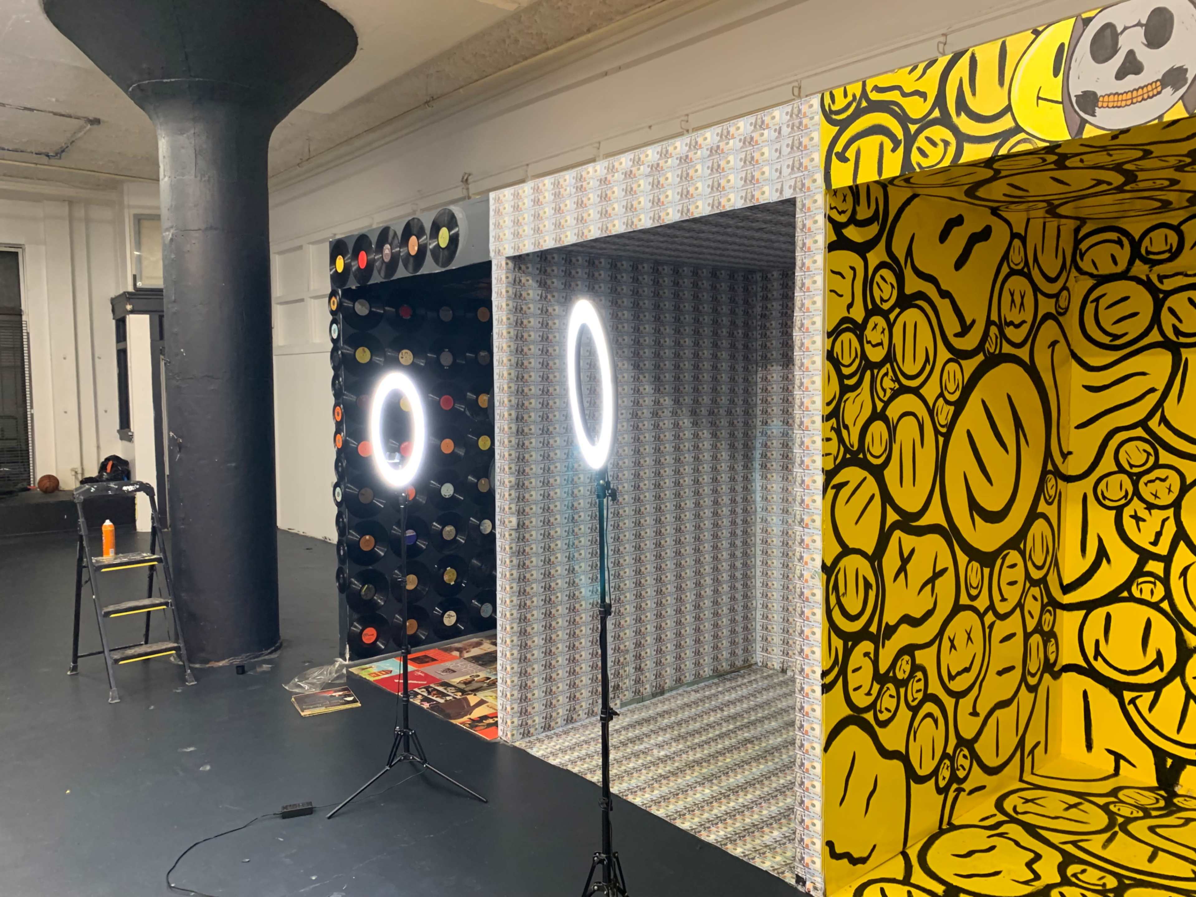 Two ring lights positioned in front of patterned backdrop walls in a studio setting.