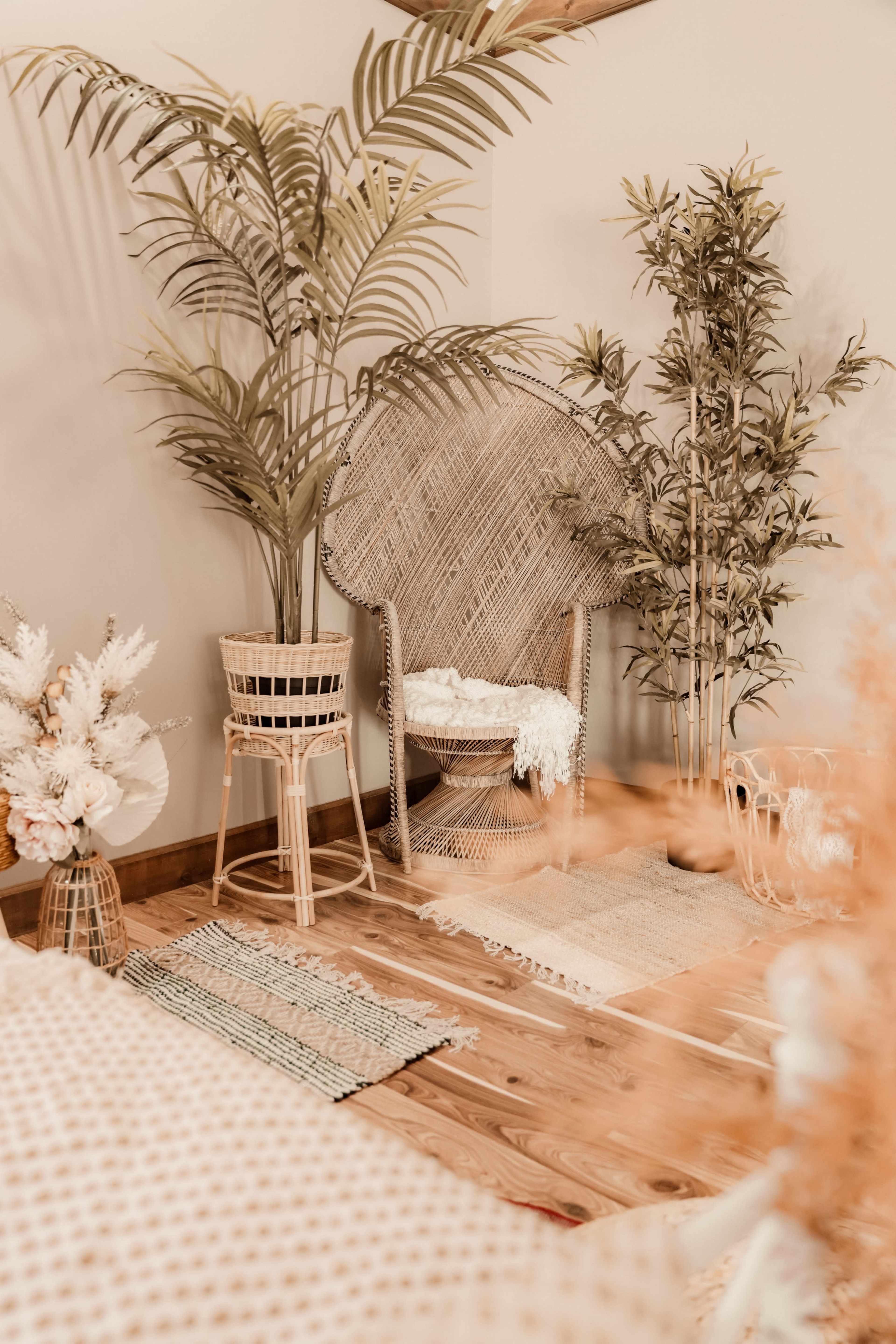 A cozy interior with a rattan chair surrounded by potted plants and decorative elements on a wooden floor.